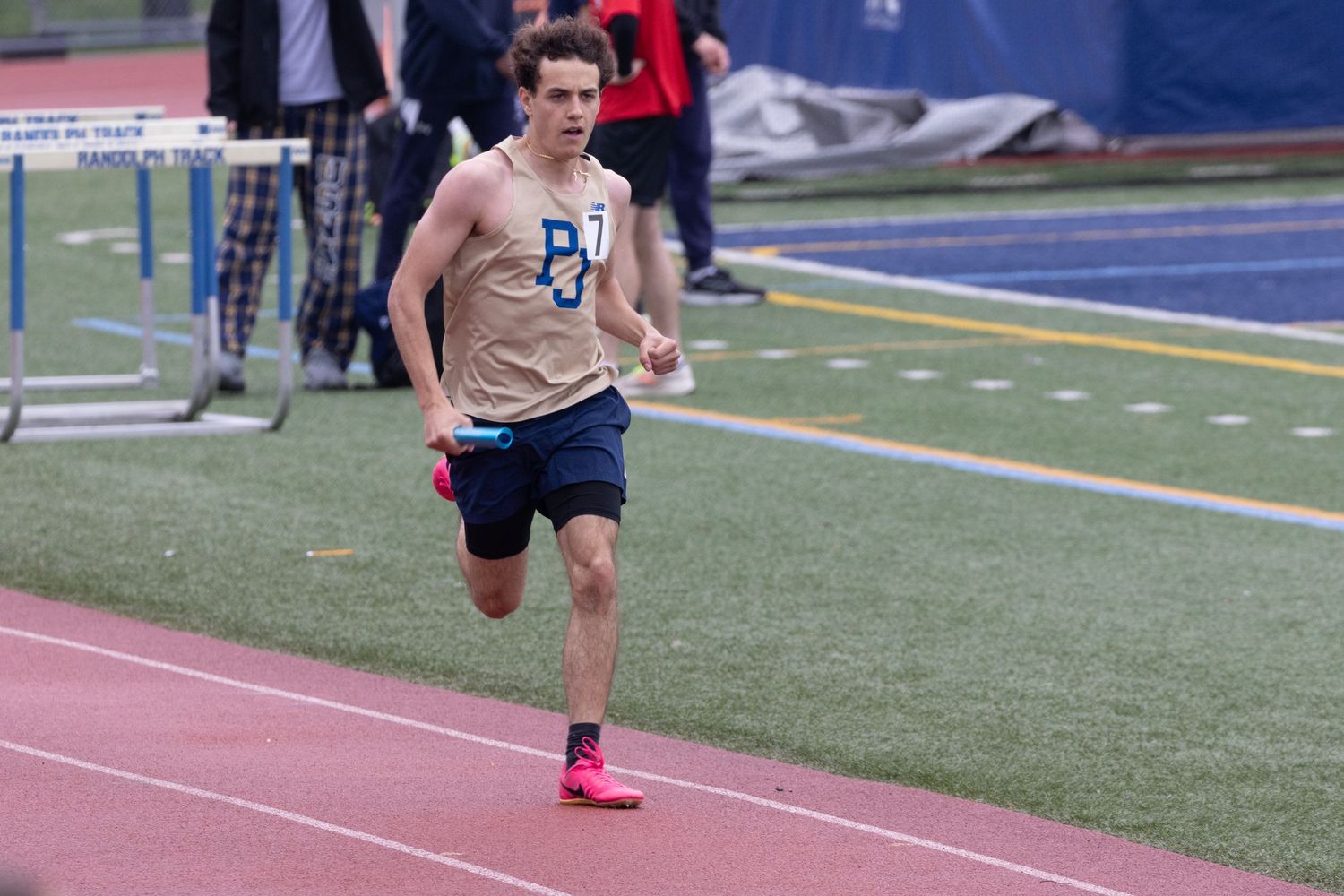 Male athlete sprinting on an outdoor blue track during a competitive track and field event.