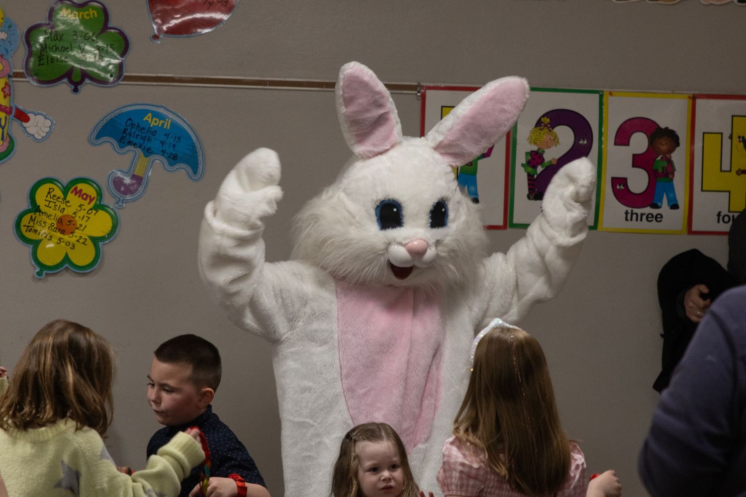 A person in an Easter Bunny costume interacts with children in a classroom.