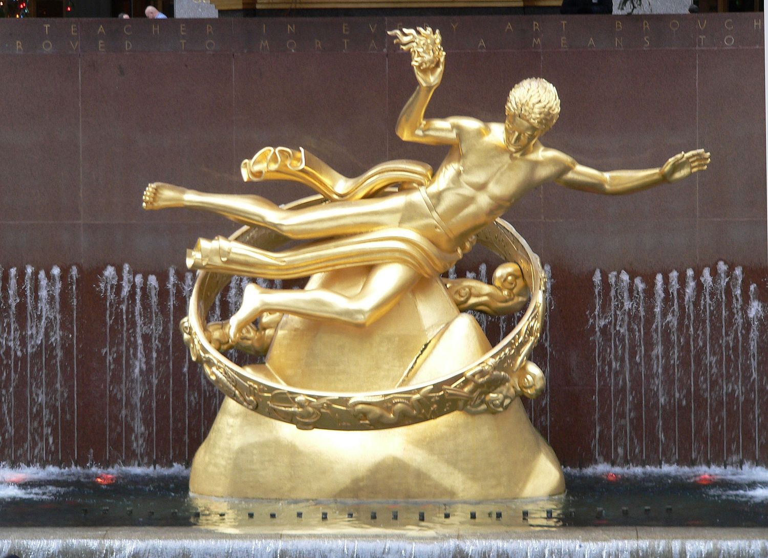 Golden Prometheus statue fountain at Rockefeller Center New York City gleaming in sunlight.