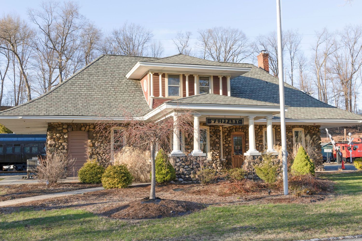 A charming brick and stone cottage-style building with a green roof and covered porch in winter.
