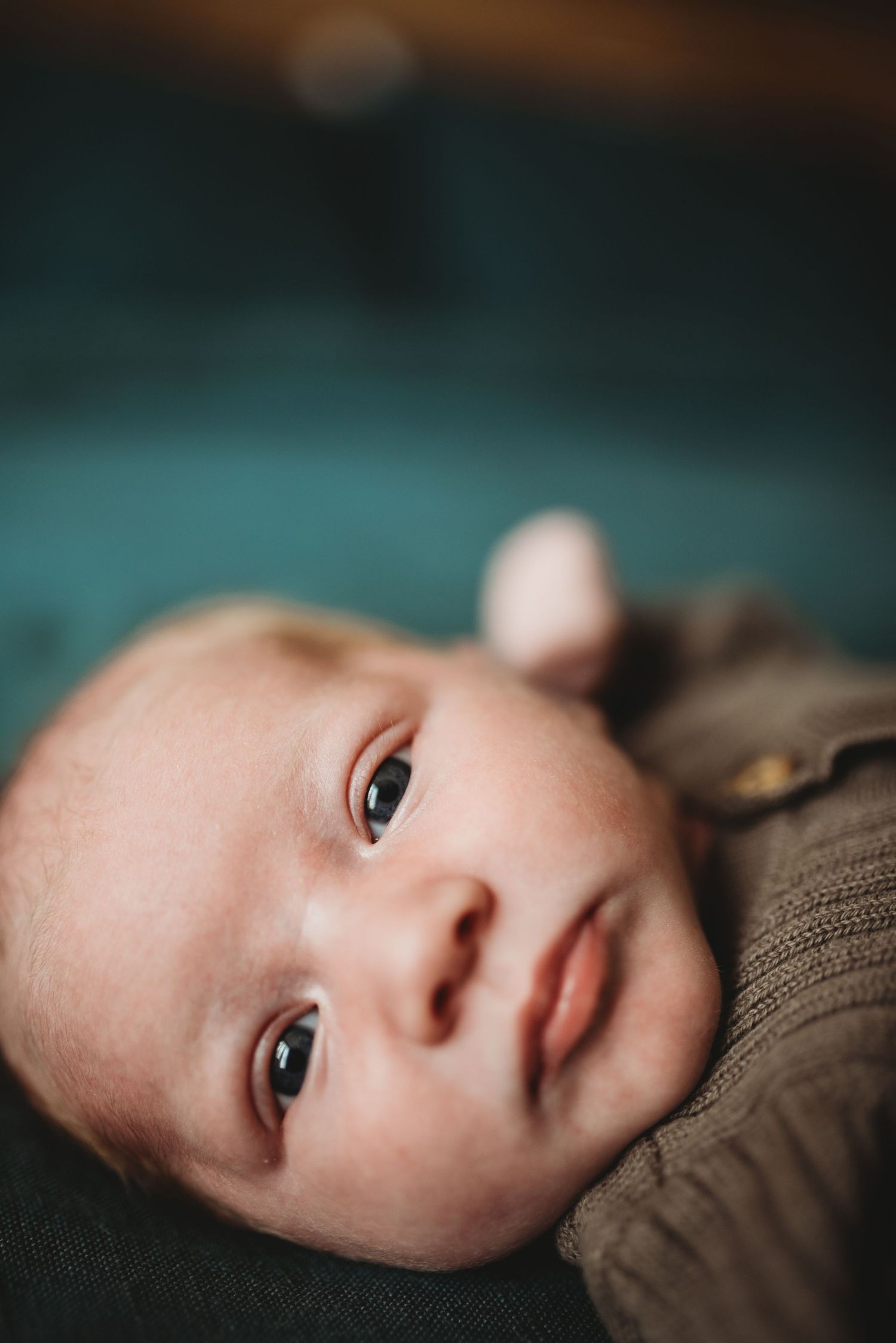 Close-up portrait of an infant with bright eyes against a dark background.