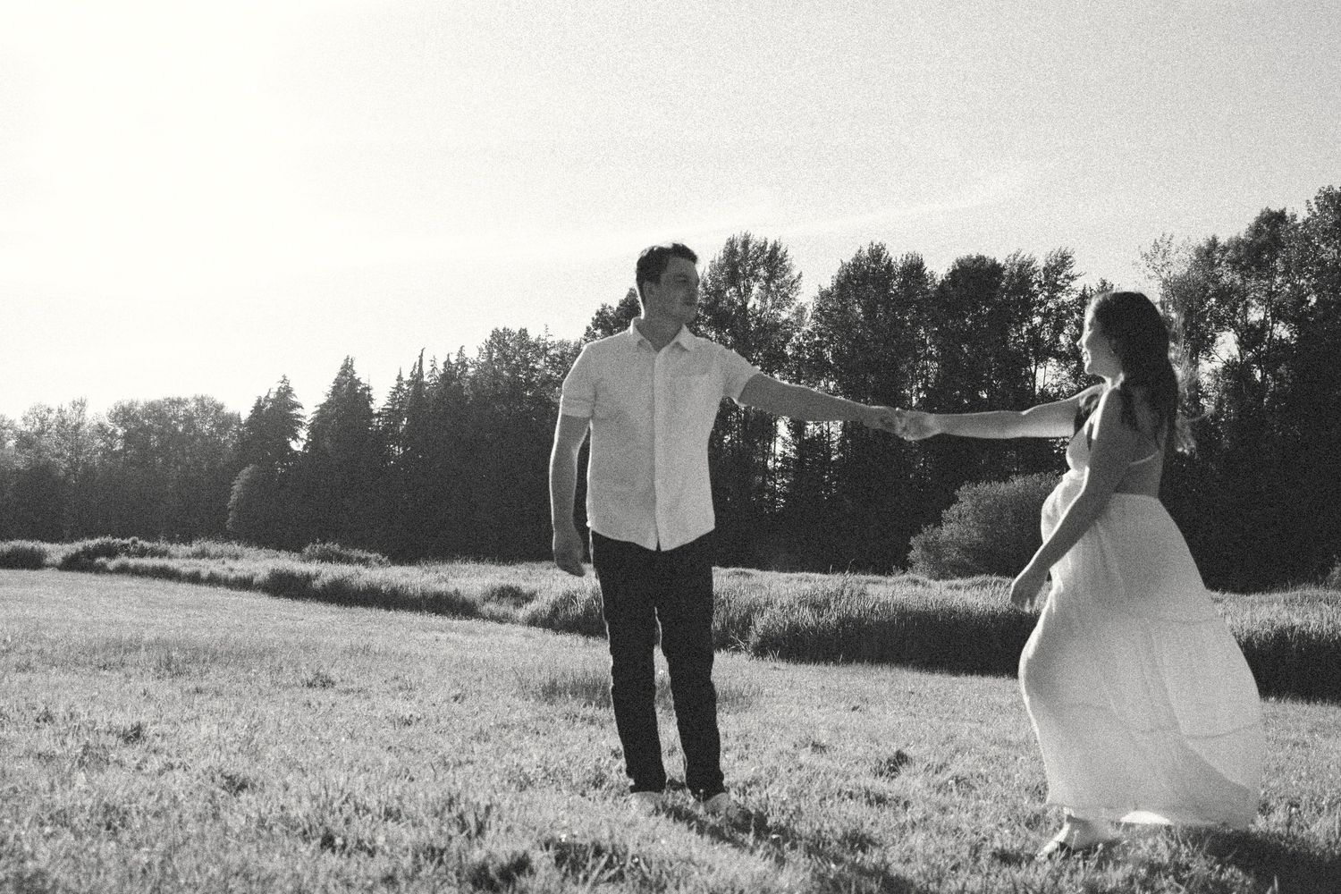 Golden hour outdoors maternity photoshoot with a couple in a field in black and white.