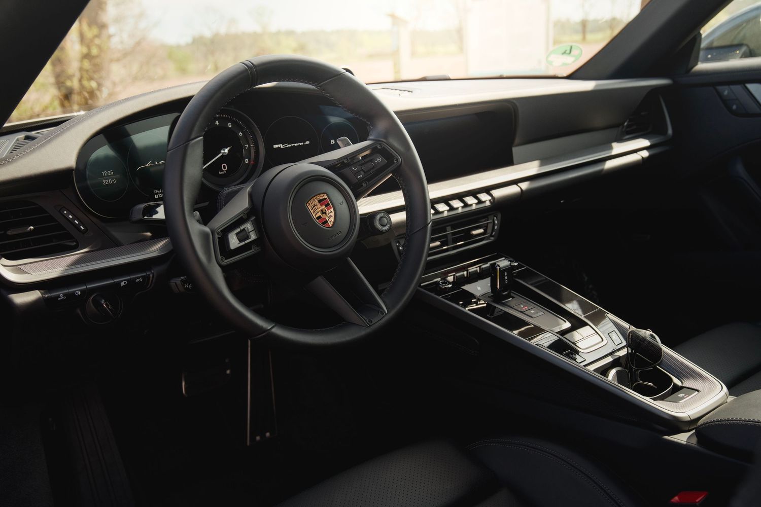 Modern Porsche interior featuring black leather dashboard and steering wheel with minimal design.