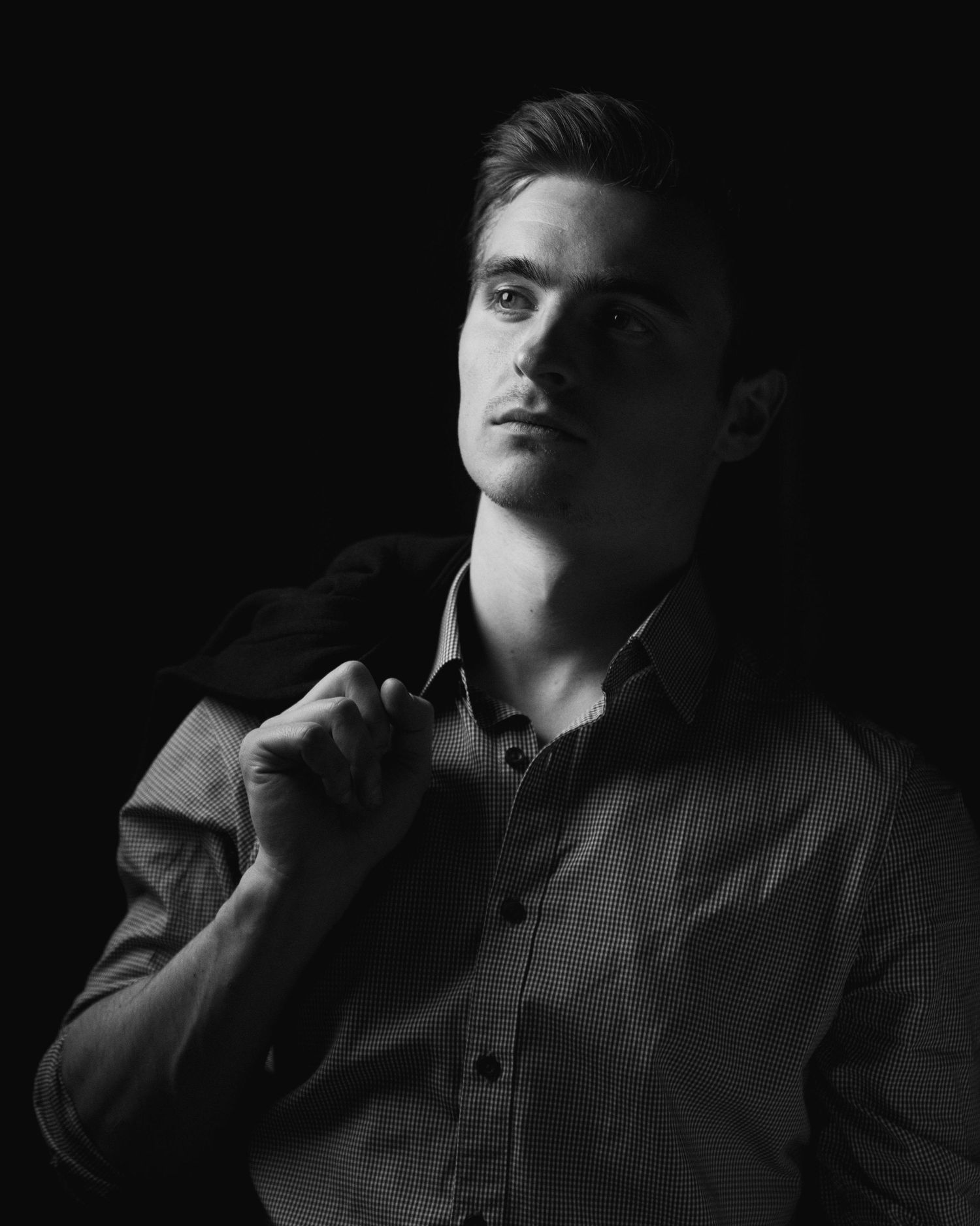 Dramatic black and white portrait lit from above creating strong shadows.