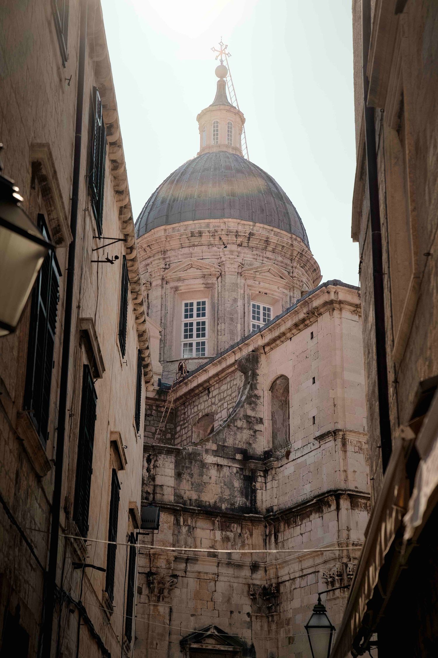 Looking up at the dome and architectural details of Dubrovnik Cathedral from narrow alleyways in Croatia.