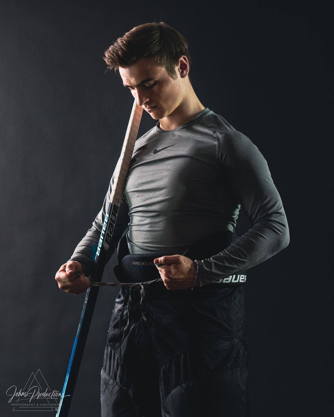 Athletic person in dark compression gear posing with workout equipment against dark background.