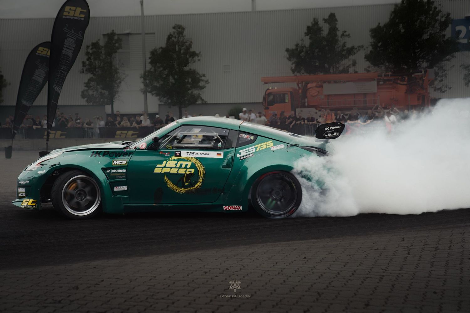 Green sports car performing a drift with tire smoke on a race track.