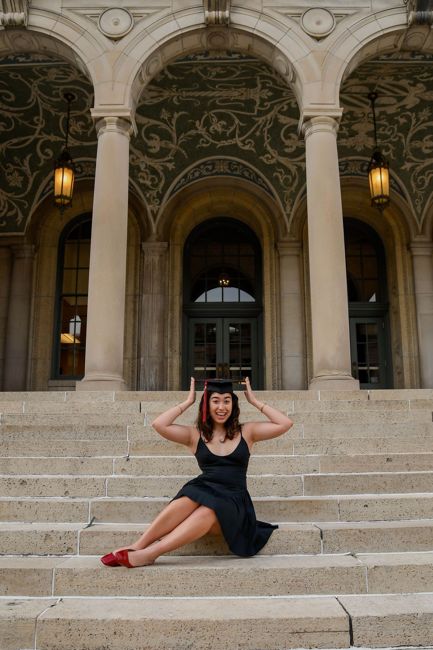 Girl sitting on steps holding her graduation cap.