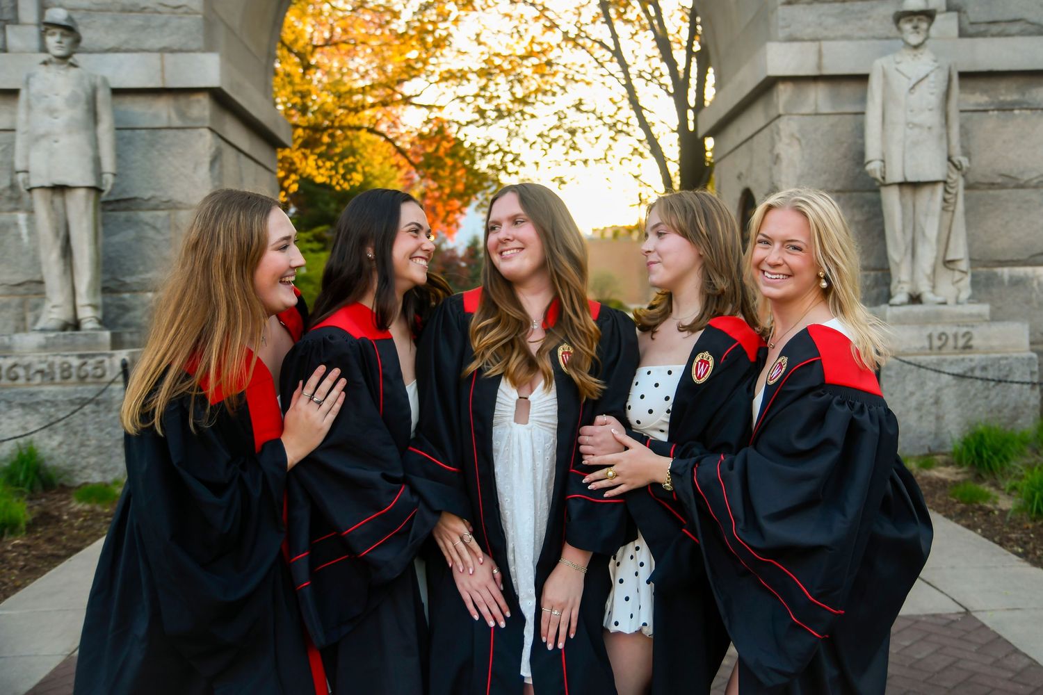 Group of girls looking at each other and smiling in their graduation gowns