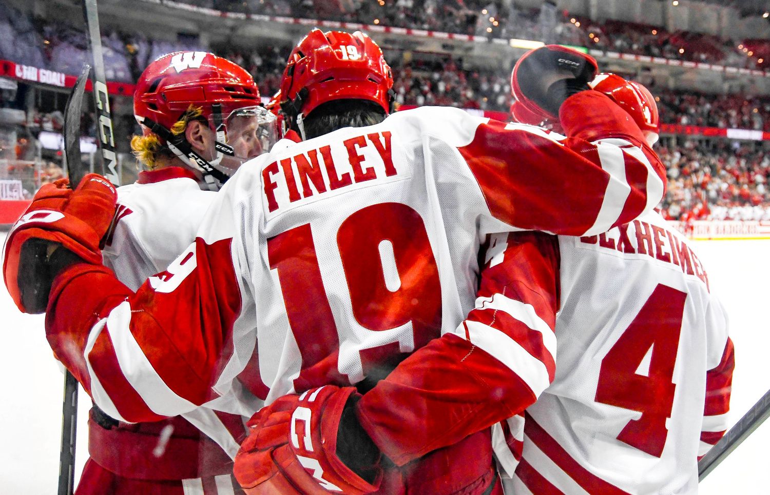 Male hockey players celebrate by putting their arms around each other