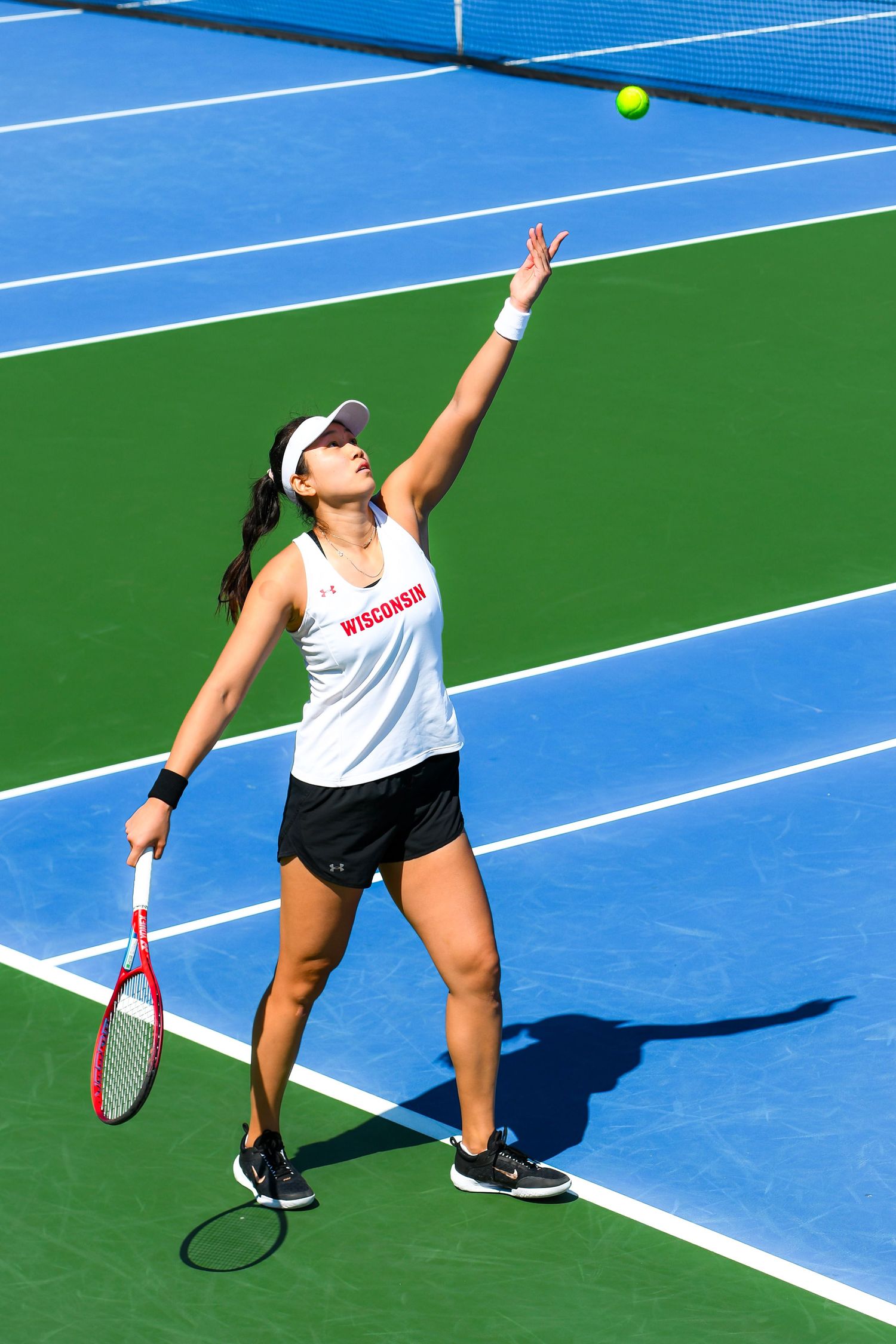 Female tennis player serves the ball on an outdoor court