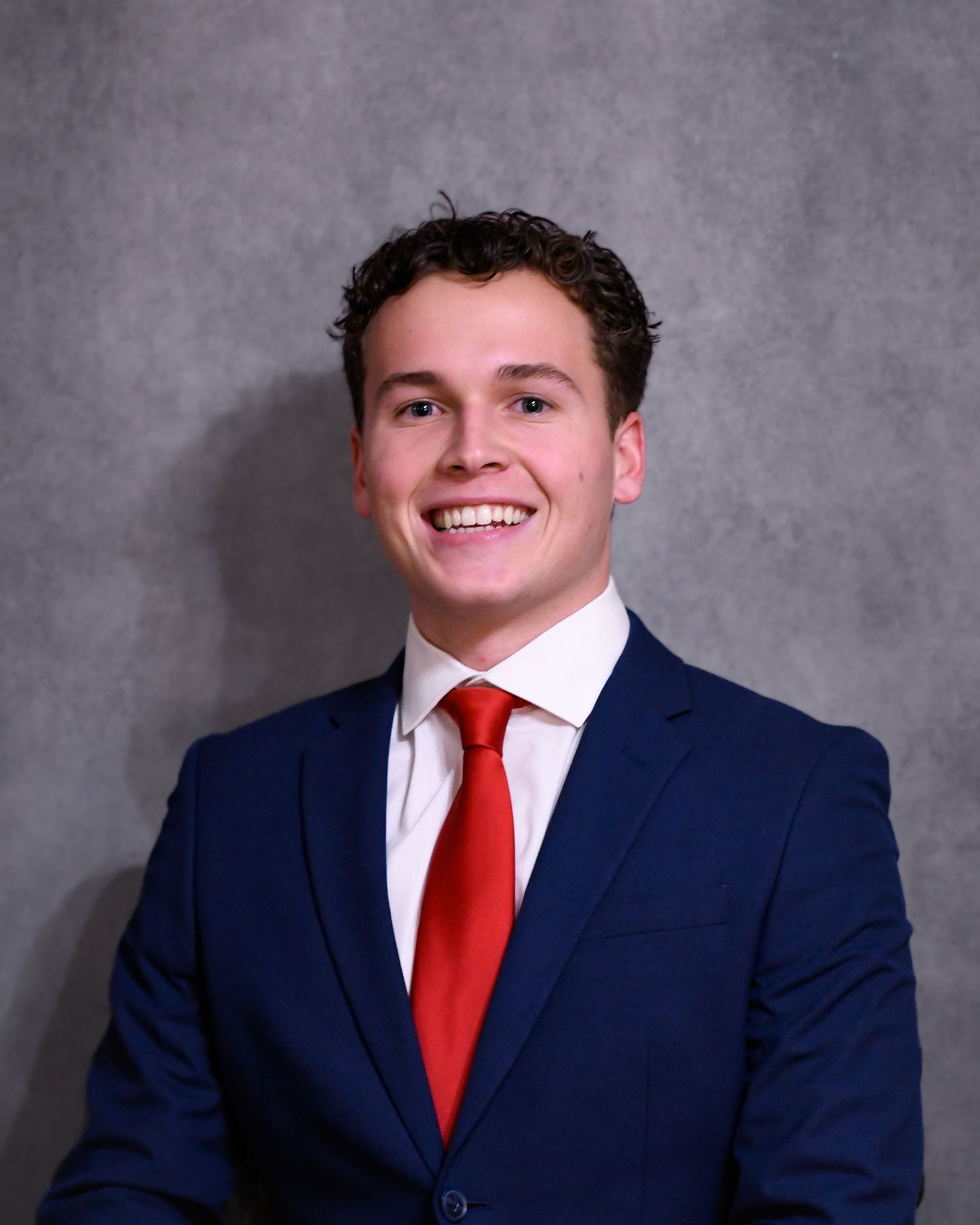 Headshot of a man in a suit and tie smiling