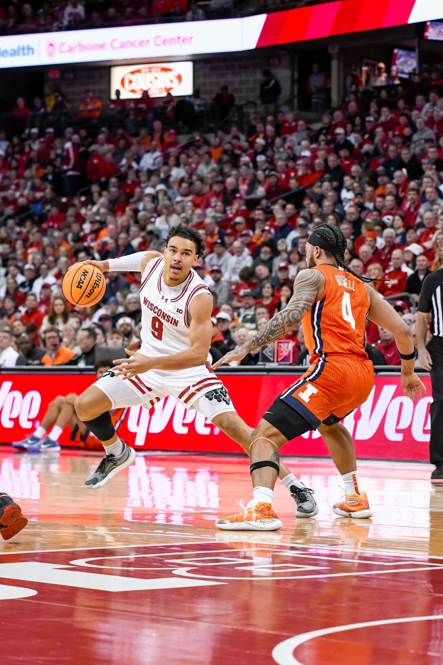 Basketball player dribbles the ball backwards away from the defender