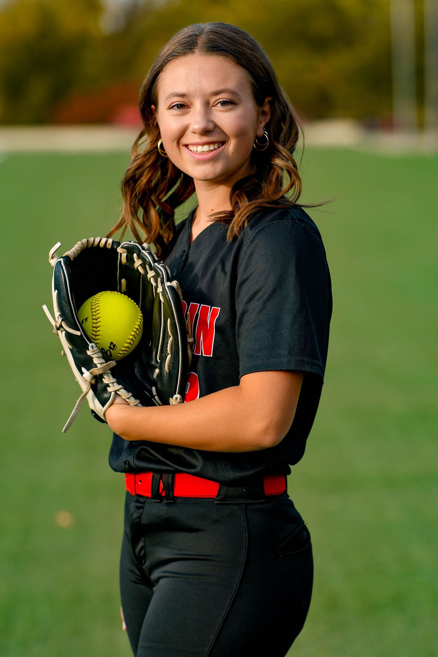 Girl smiling holding a softball in a glove