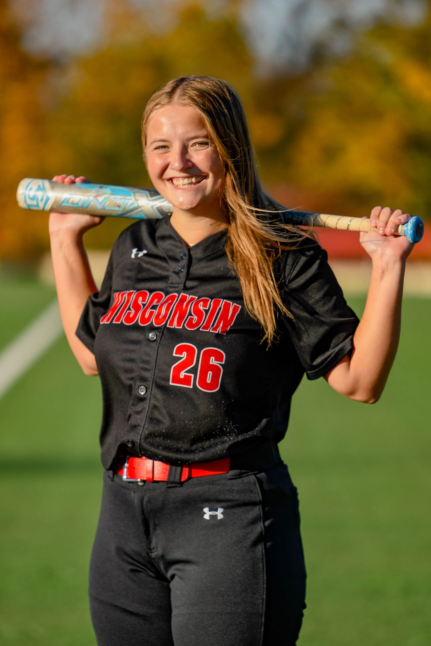 Girl smiling holding a bat behind her back