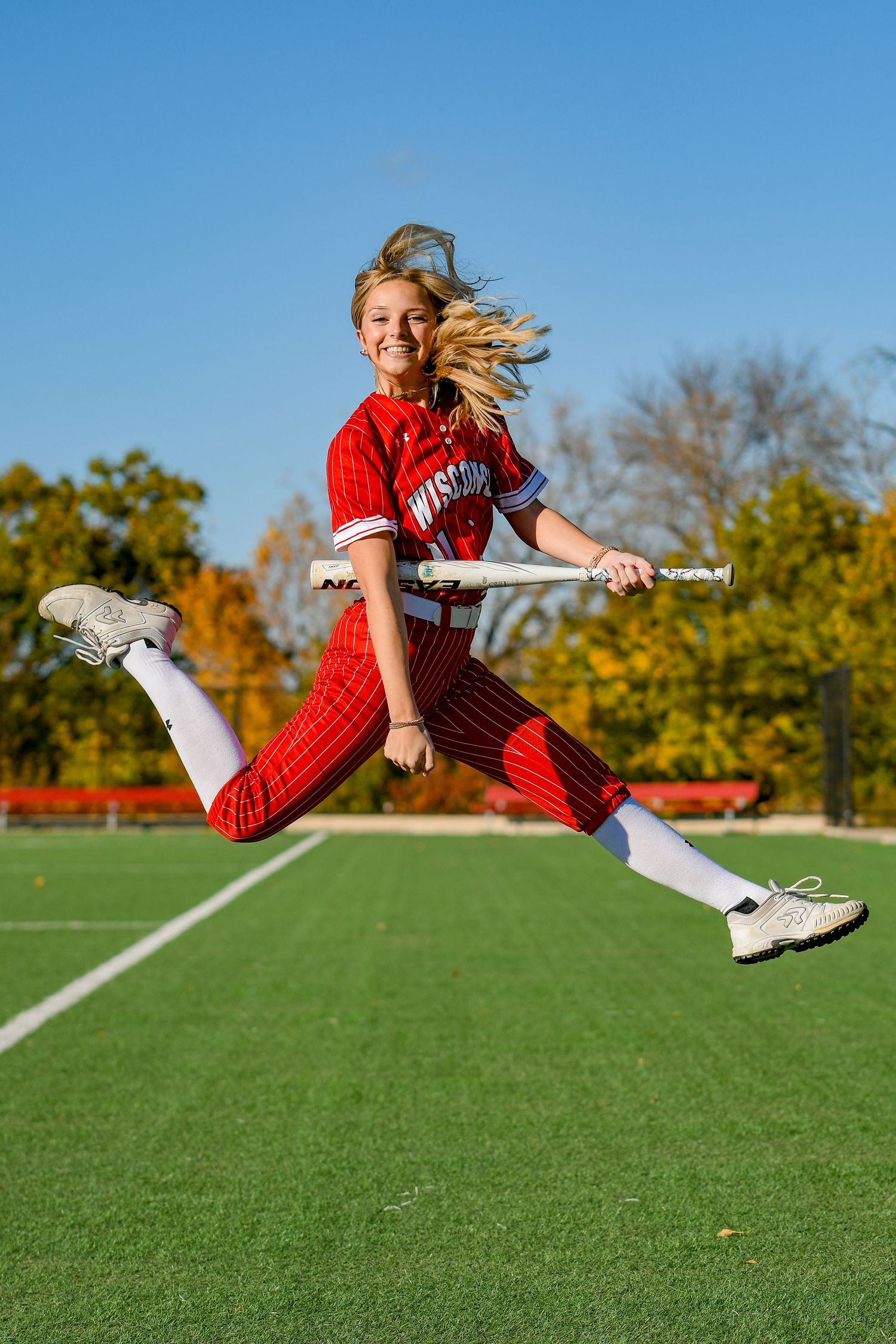 Girl smiling while jumping in the air strumming a bat like a guitar