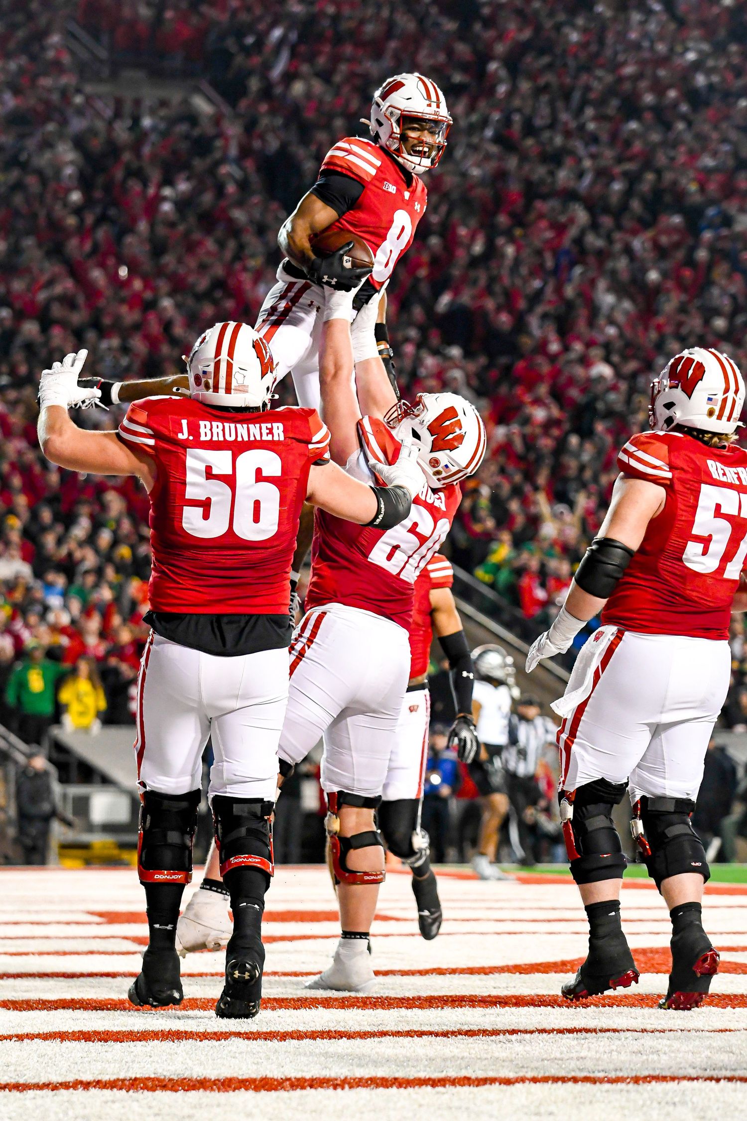 Football player lifts teammate off the ground in celebration