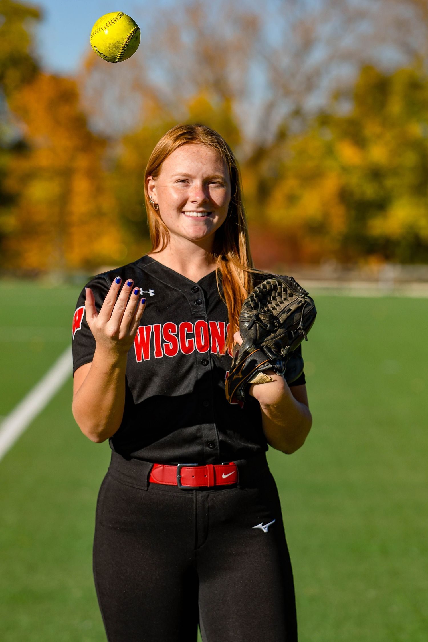 Girl smiling and throwing a softball in the air