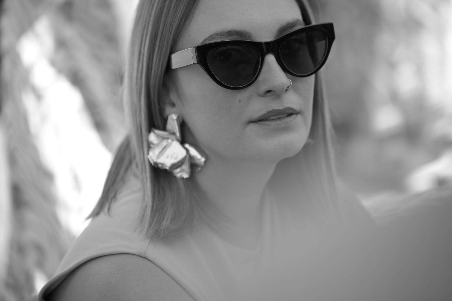 Black and white portrait series showing a person wearing sunglasses in different poses against a blurred background.