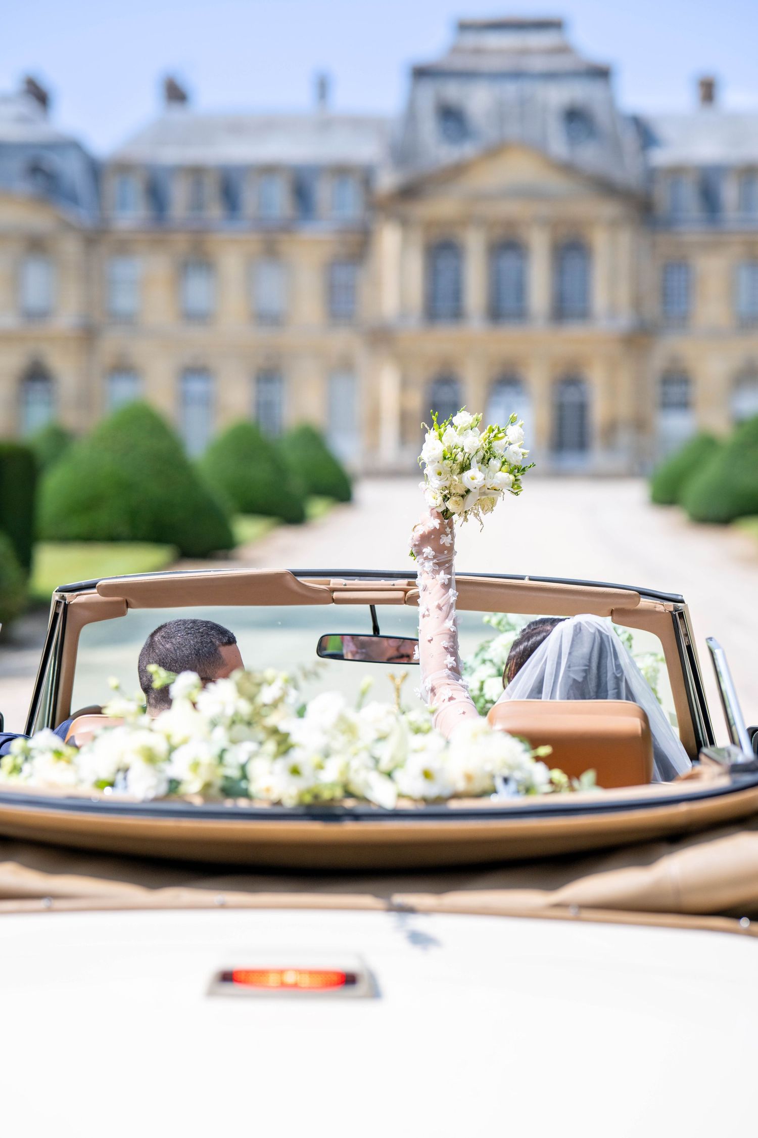 Classic vintage car parked in front of an elegant French chateau.