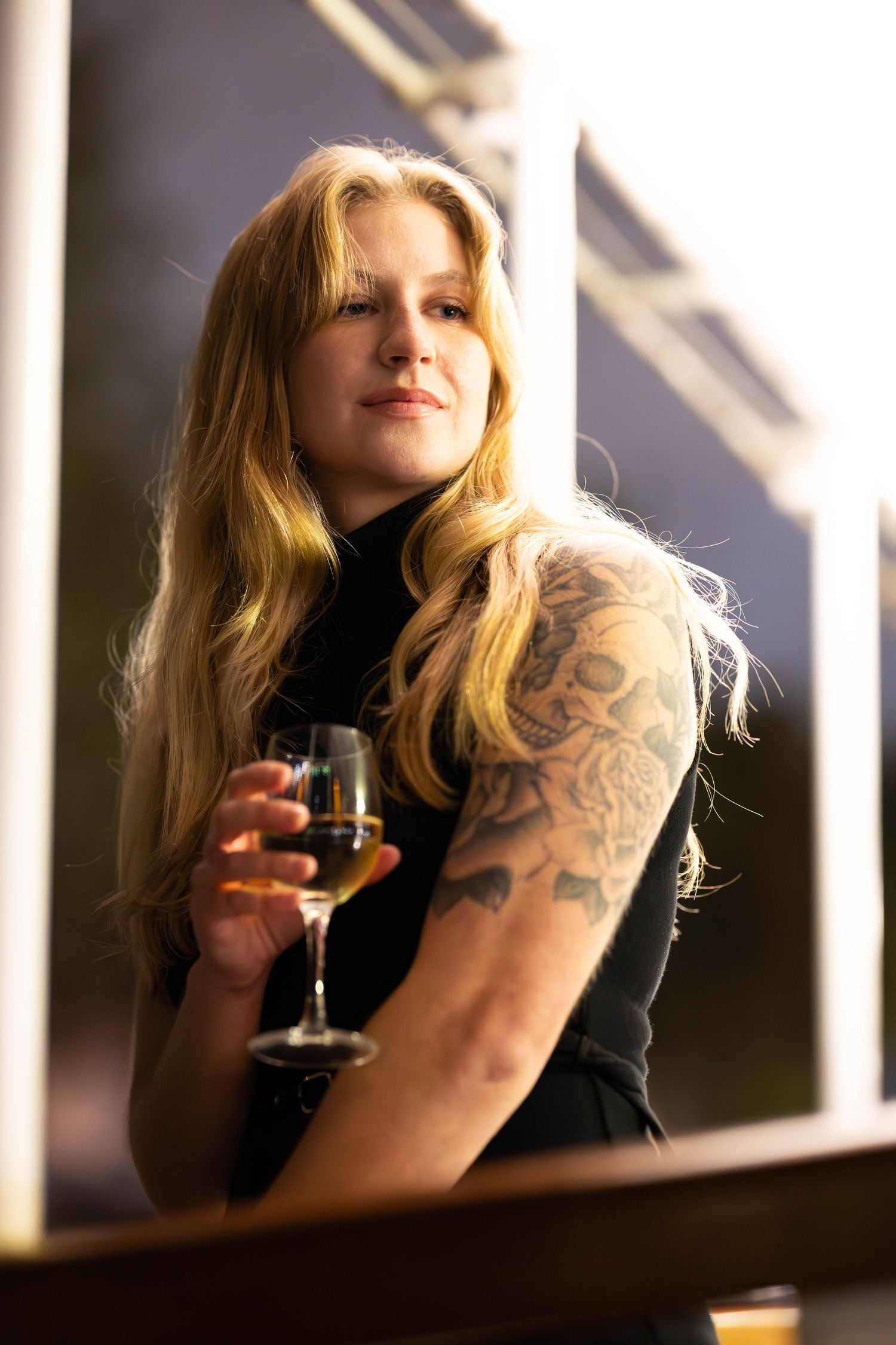 A series of artistic photos showing someone with blonde hair drinking wine in dramatic window lighting.