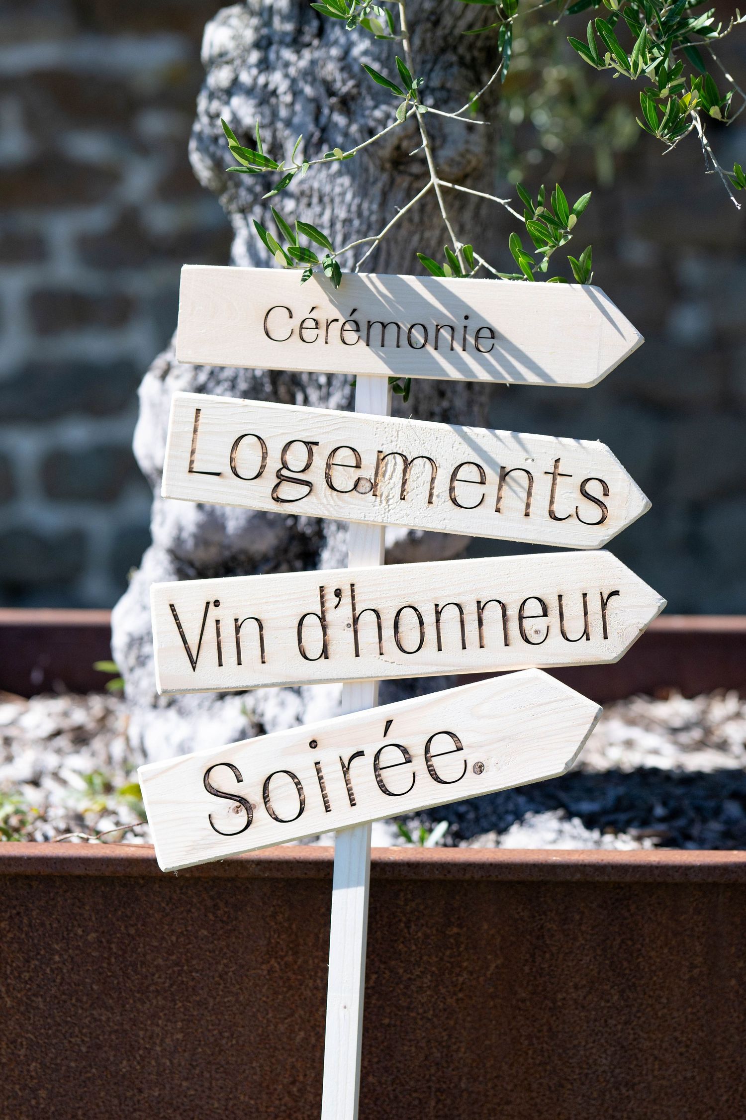 Rustic wooden directional signs in French for wedding ceremony and reception.