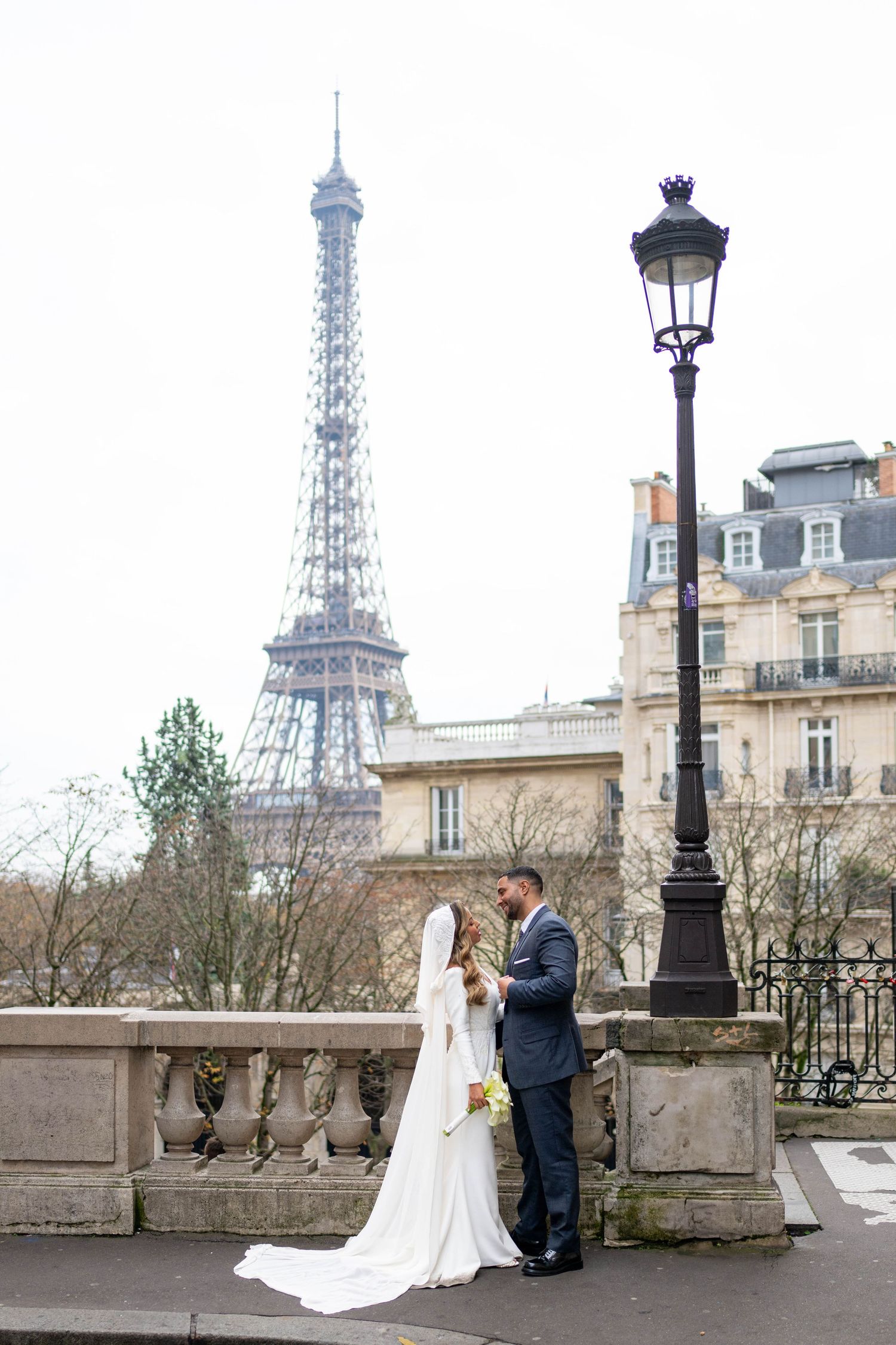 Wedding couple poses for romantic portraits along a Parisian street with the Eiffel Tower in background.