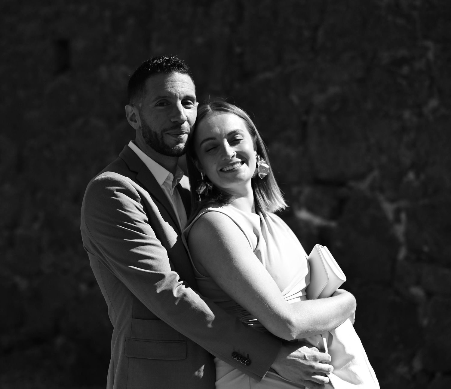 A romantic black and white wedding photo shows a couple embracing in a tender moment.