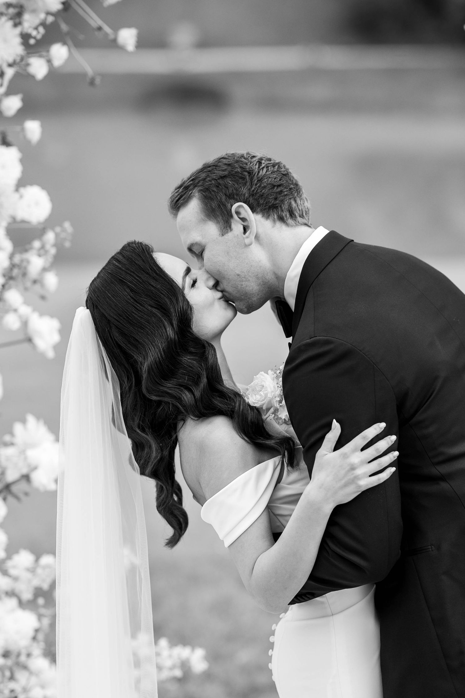 A romantic black and white wedding photo series showing a couple in an intimate dip kiss pose.