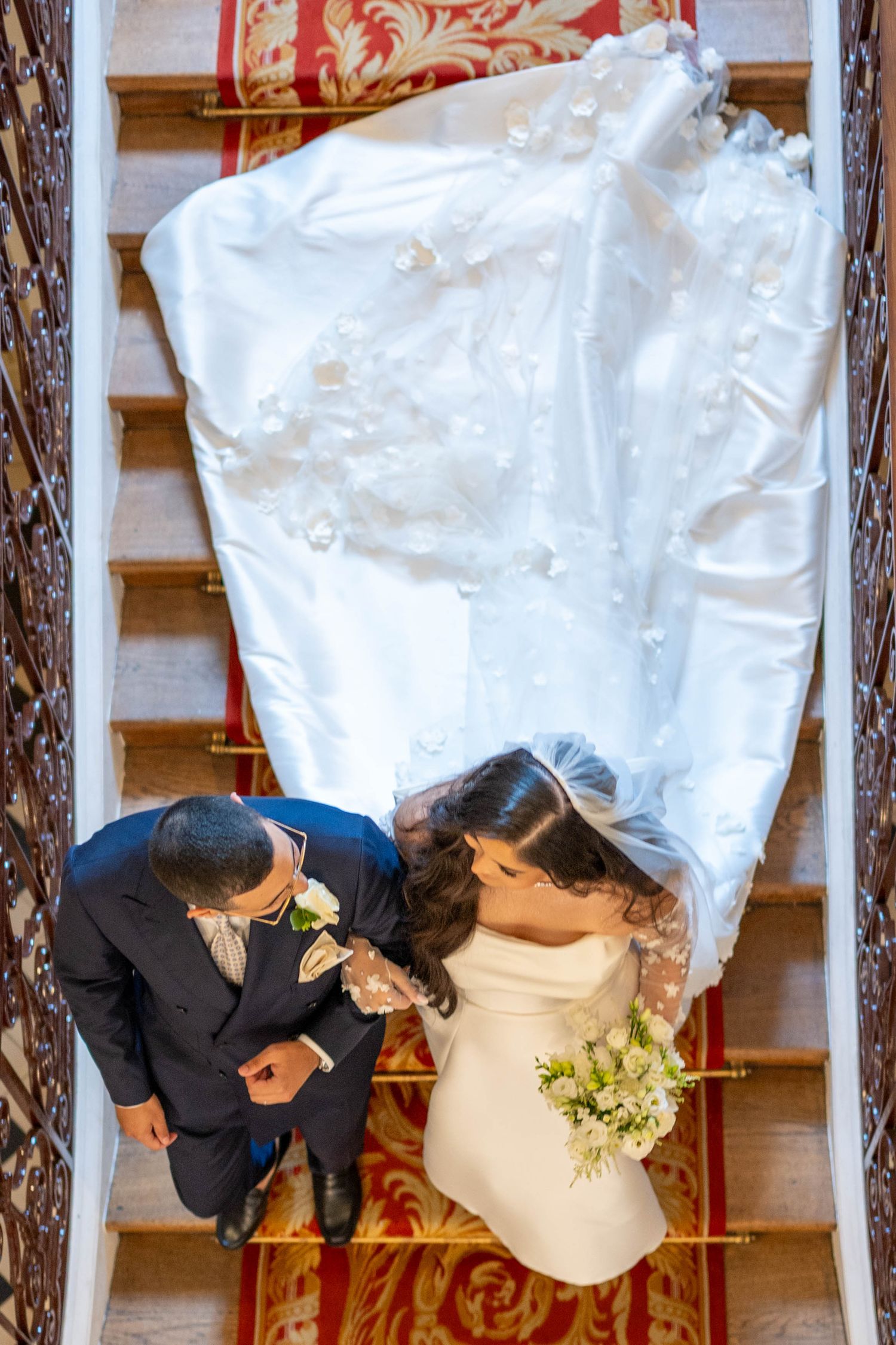 Aerial view of a couple sharing a romantic kiss during their wedding ceremony under white fabric draping decorations.