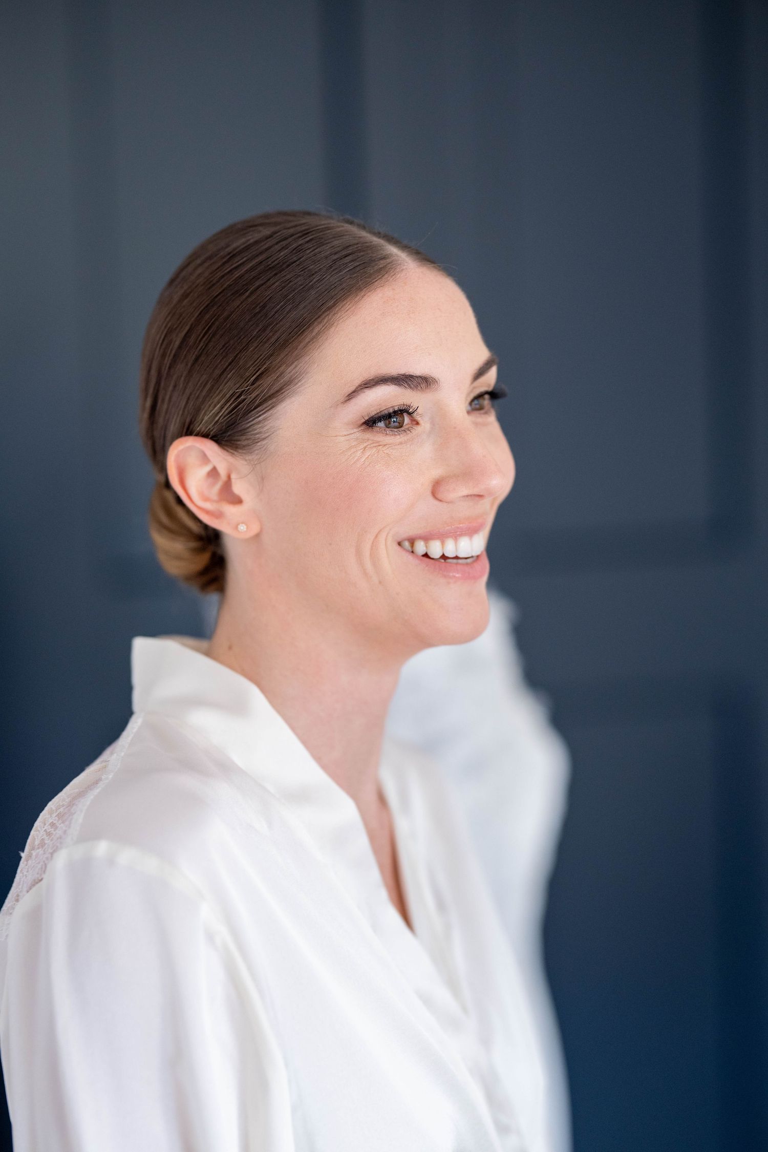 A woman in a white bathrobe smiles warmly in a sequence of profile shots against a dark blue background.