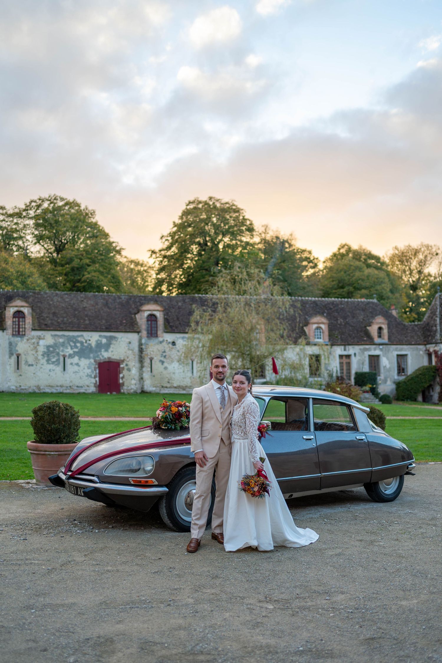 Classic vintage car parked outside stone building for wedding photos at sunset.