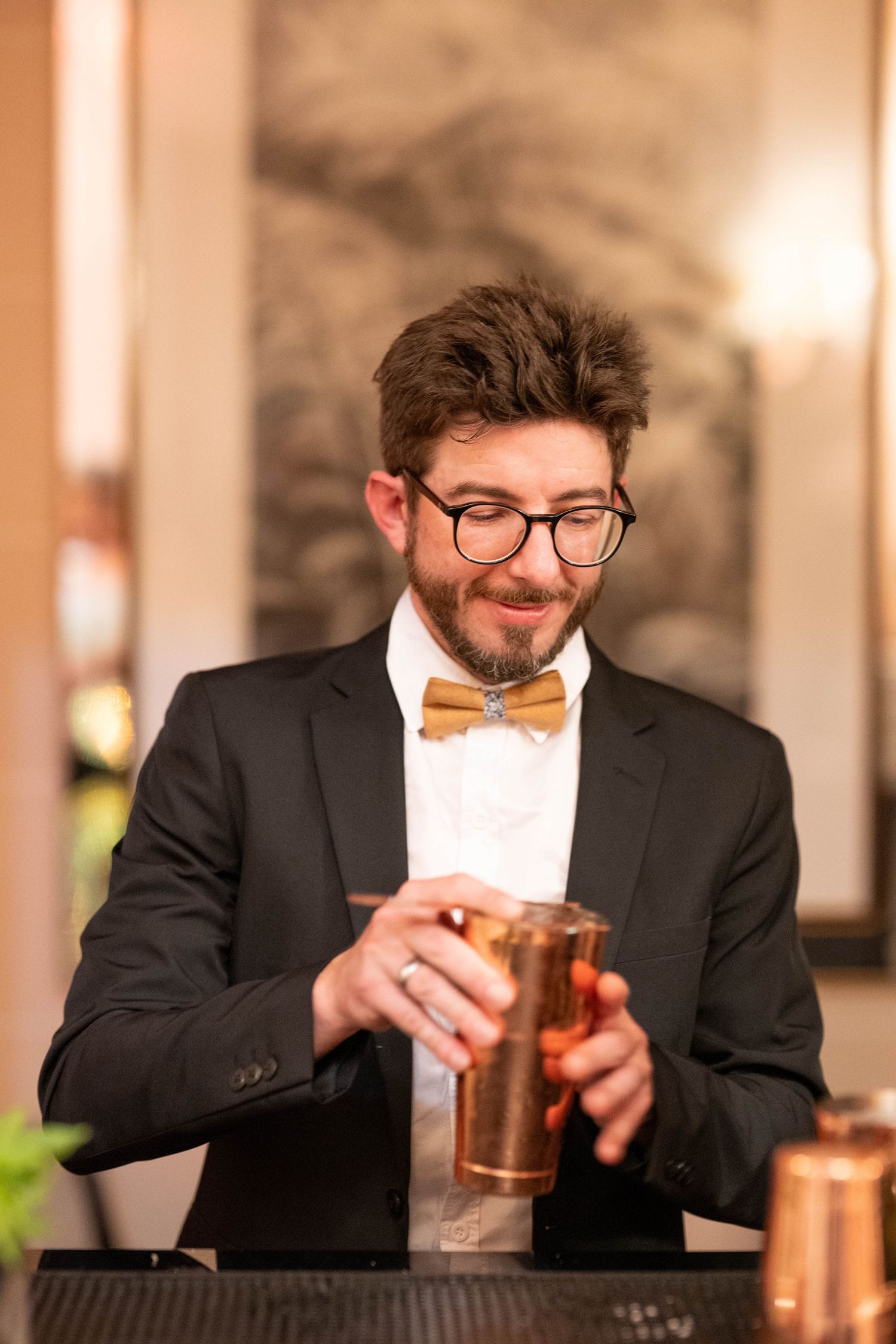 A sequence of photos showing a person in a suit and glasses enjoying a cocktail at a bar counter.