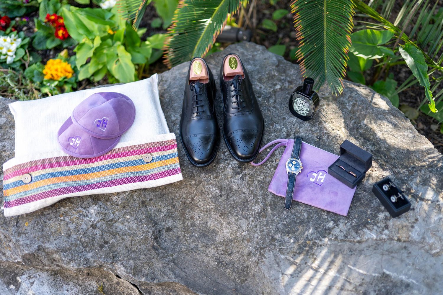 Wedding accessories and formal shoes arranged on natural stone surface.