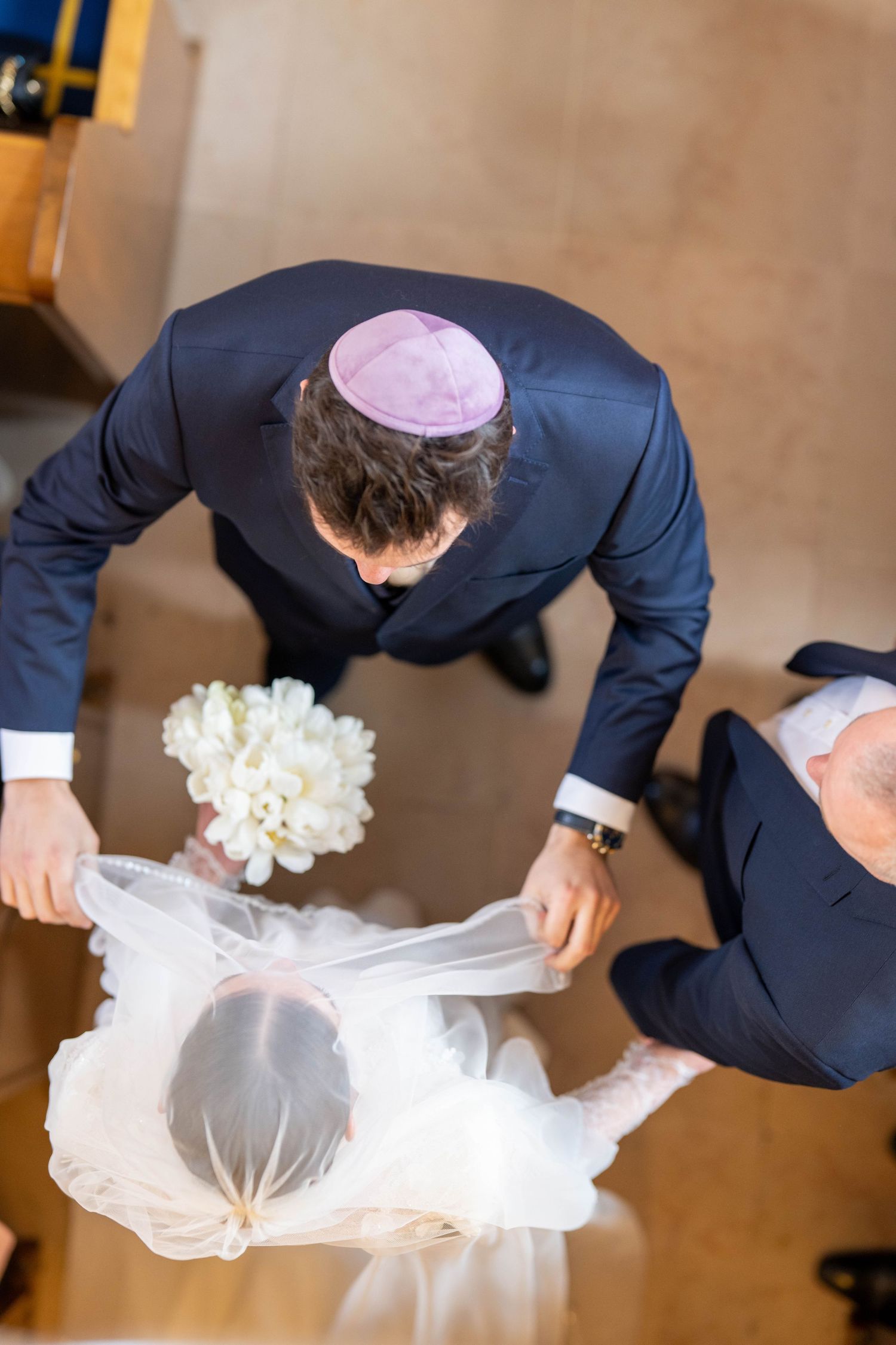 Rabbi carefully inspects and adjusts a white tallit prayer shawl before a religious ceremony.