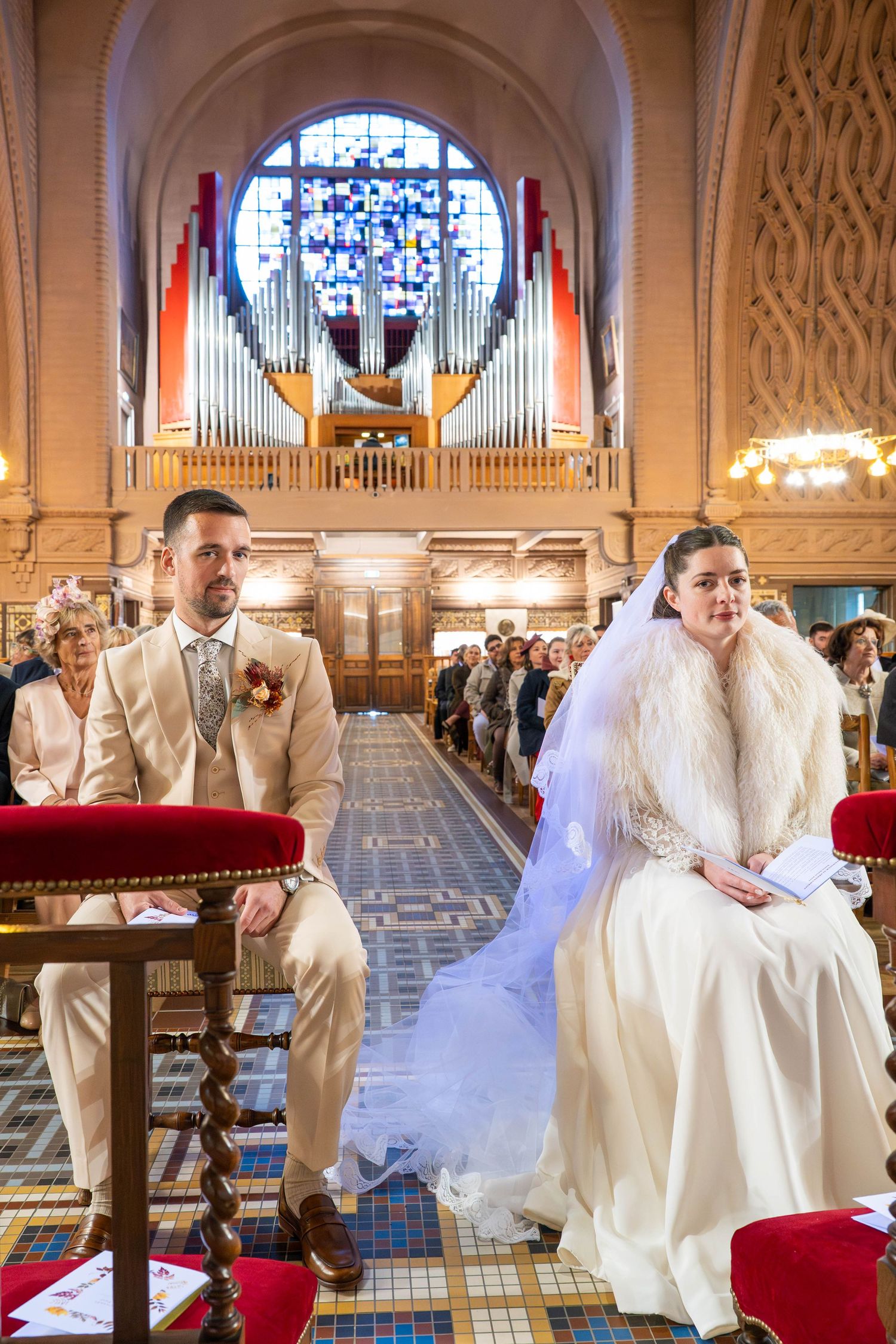 Wedding couple poses playfully in an ornate church interior with elegant white and cream decor.