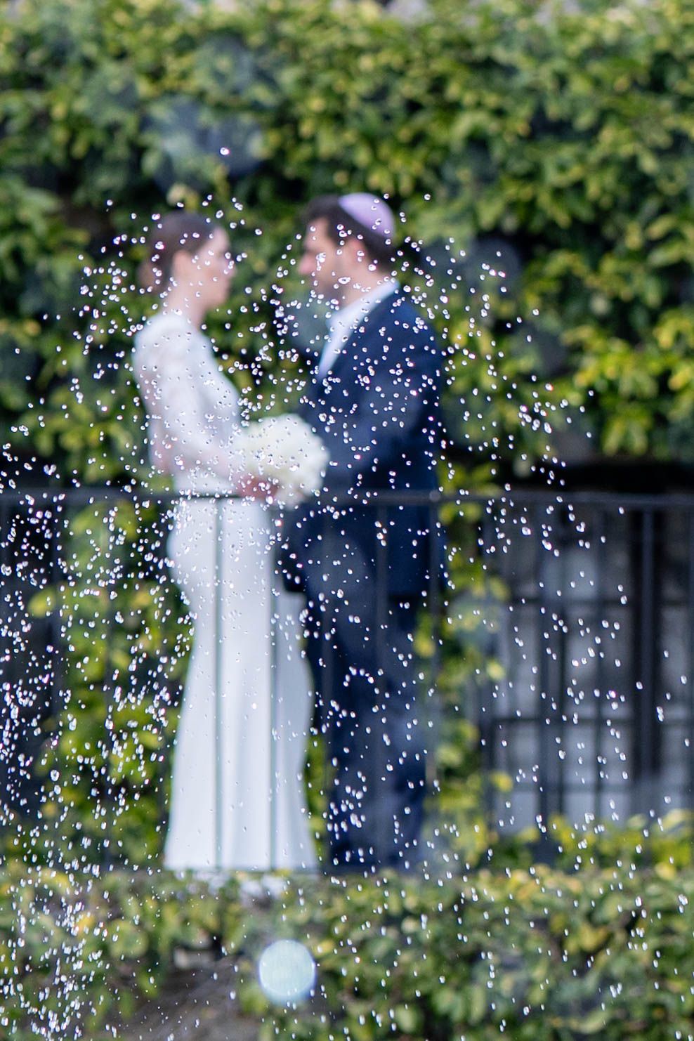 Wedding couple surrounded by falling confetti in garden celebration.