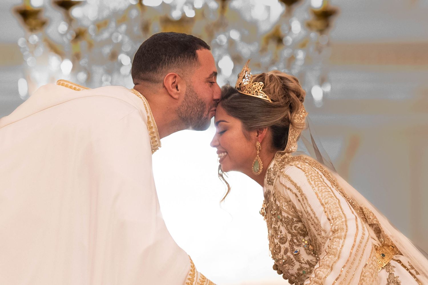 Romantic couple moment captured under an ornate crystal chandelier.