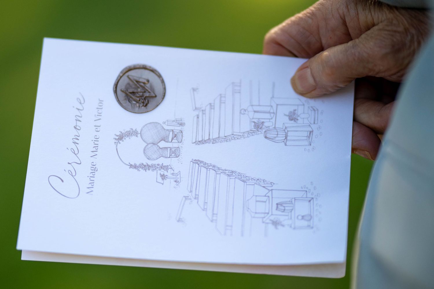 Hand holding a notebook with pencil sketches showing design concepts and architectural drawings.