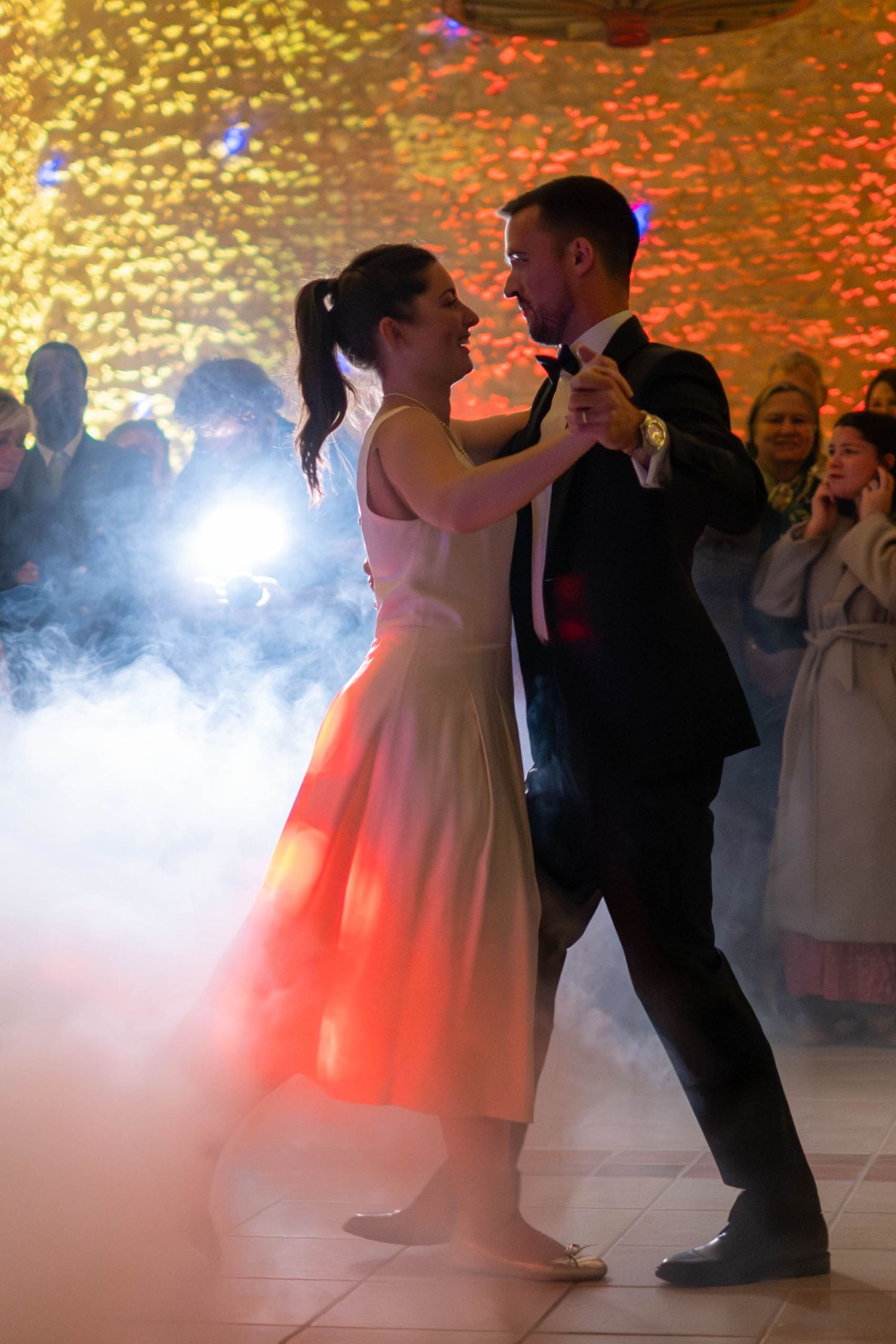 First dance at wedding reception with dramatic lighting and fog effect on dance floor.