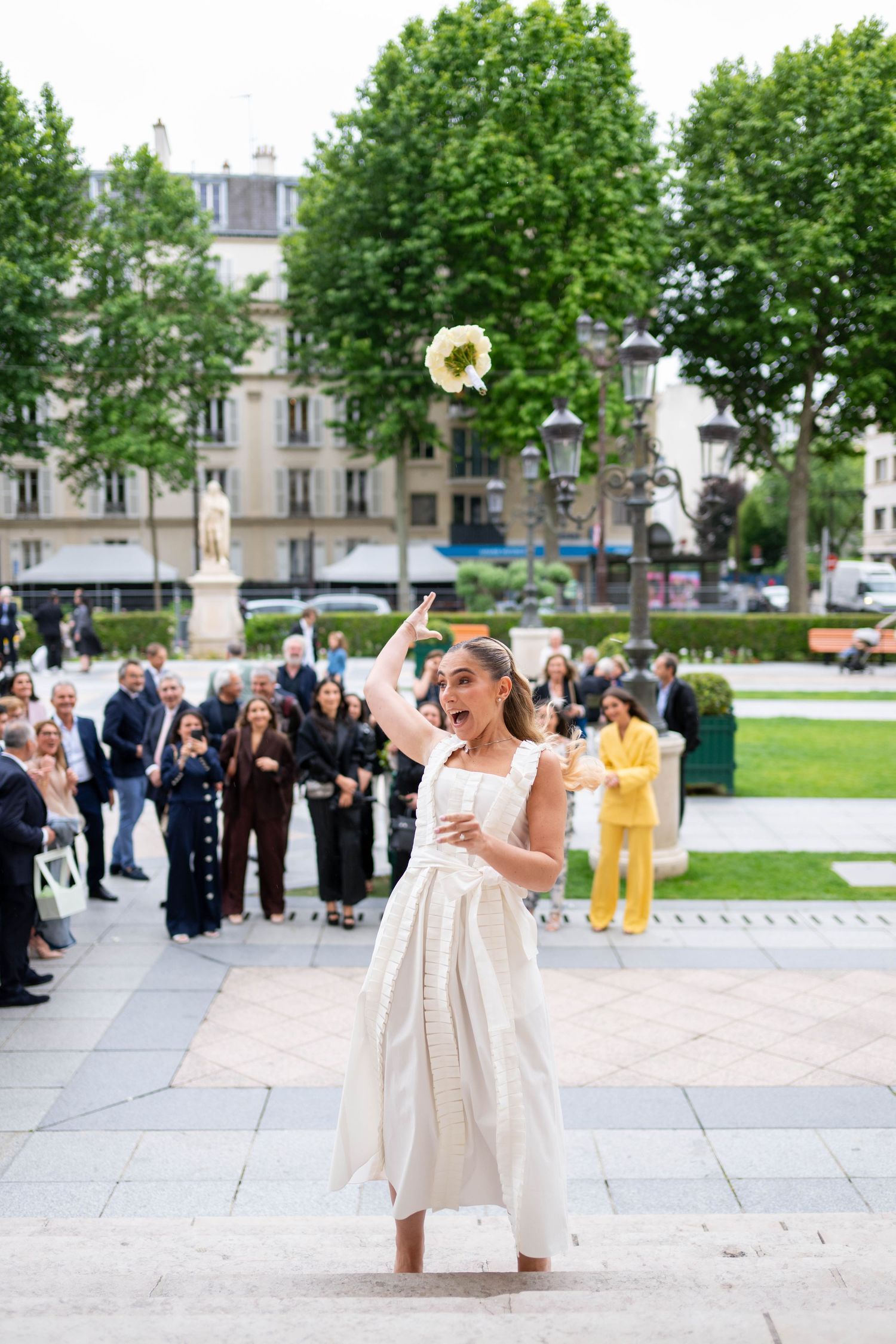 A joyful moment captured at an outdoor wedding ceremony as someone in a white dress twirls on a stone patio.