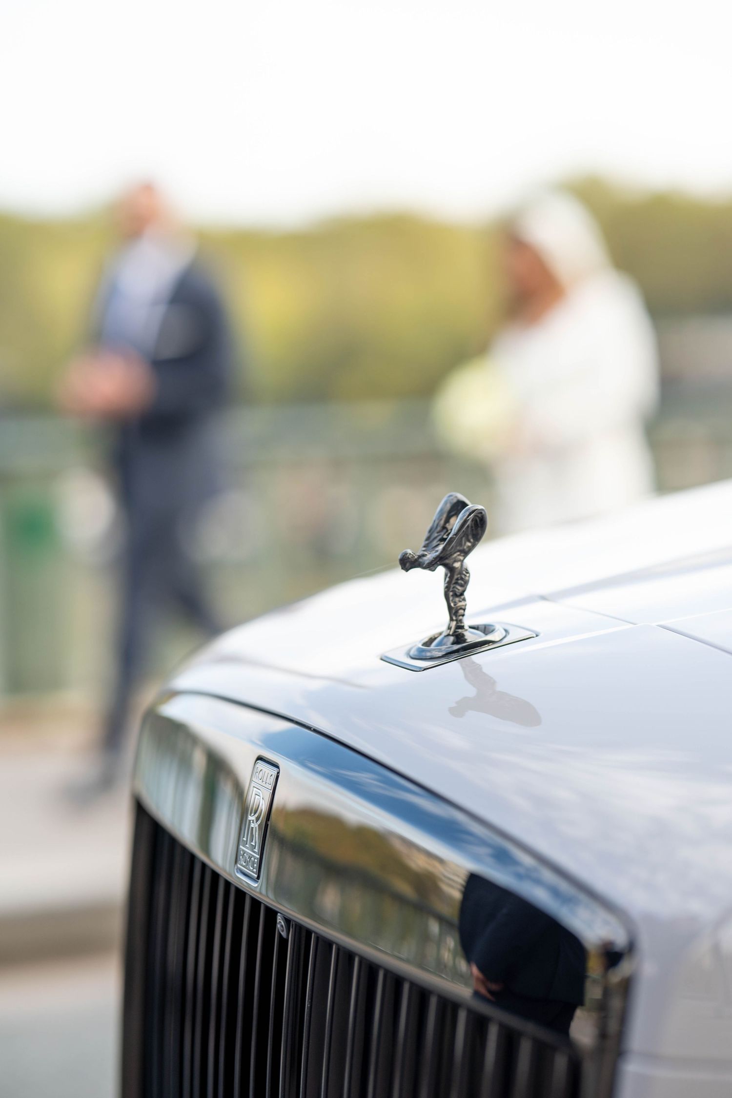 Close-up detail of a Rolls Royce's iconic Spirit of Ecstasy hood ornament and grille.