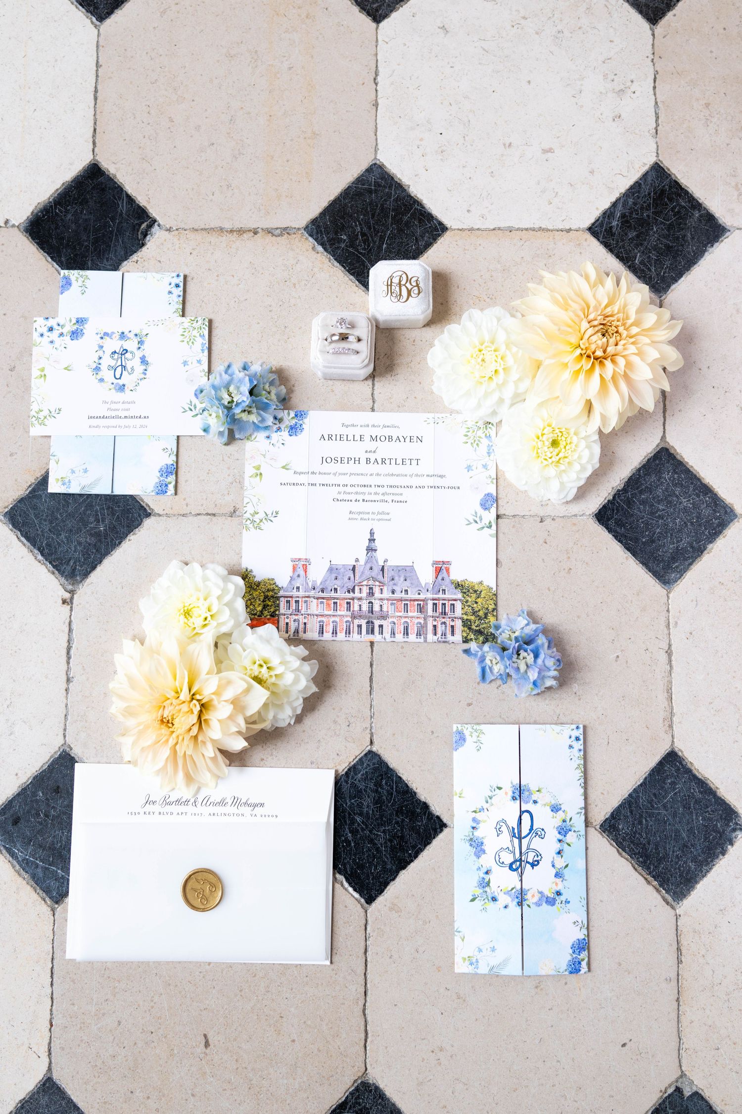 Wedding stationery and yellow flowers arranged on black and white checkered tile flooring.