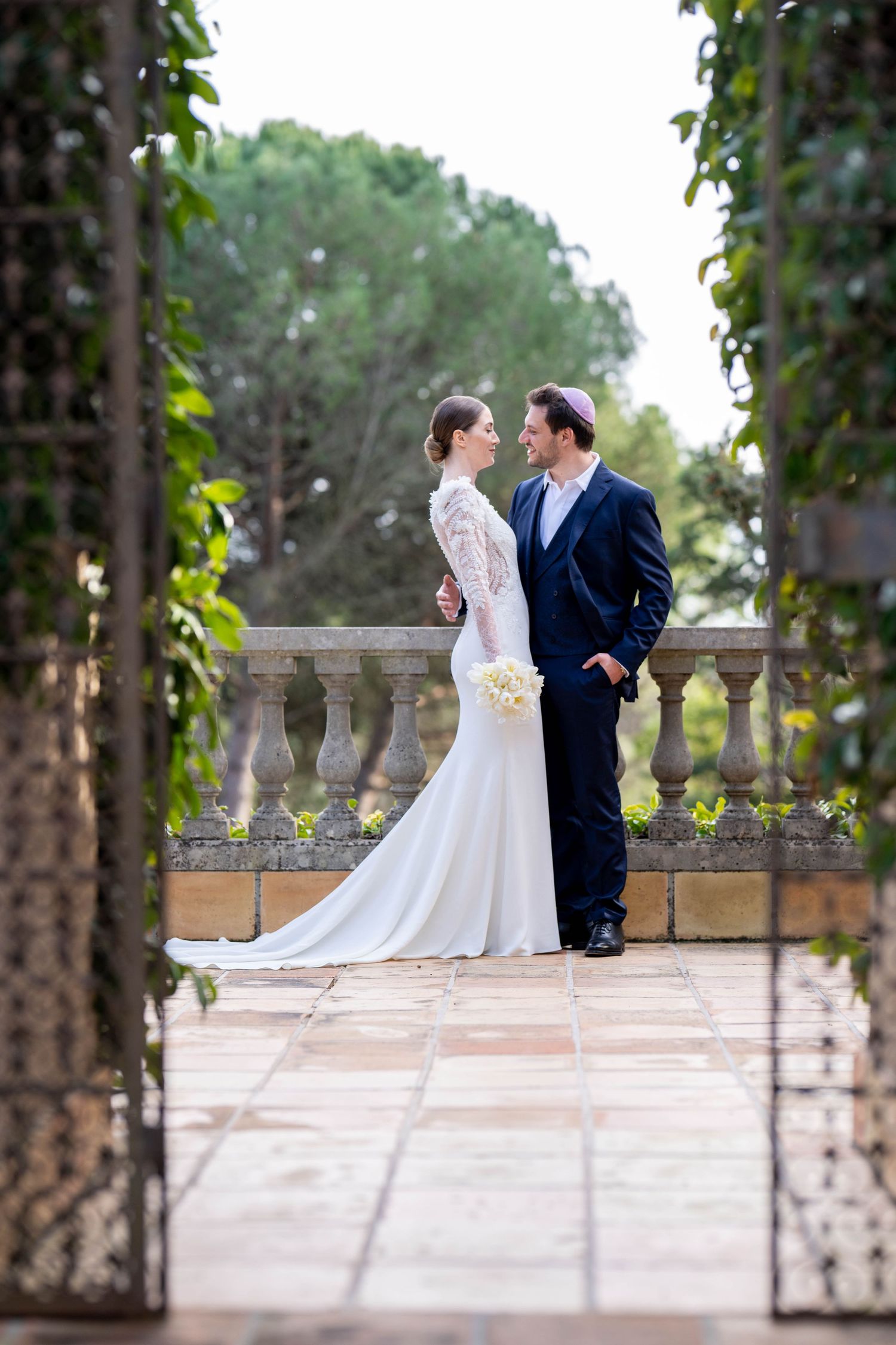 Wedding couple sharing intimate moment on elegant stone terrace.