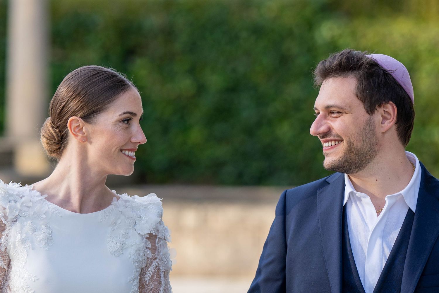 A bride and groom share a joyful moment together outdoors in elegant wedding attire.