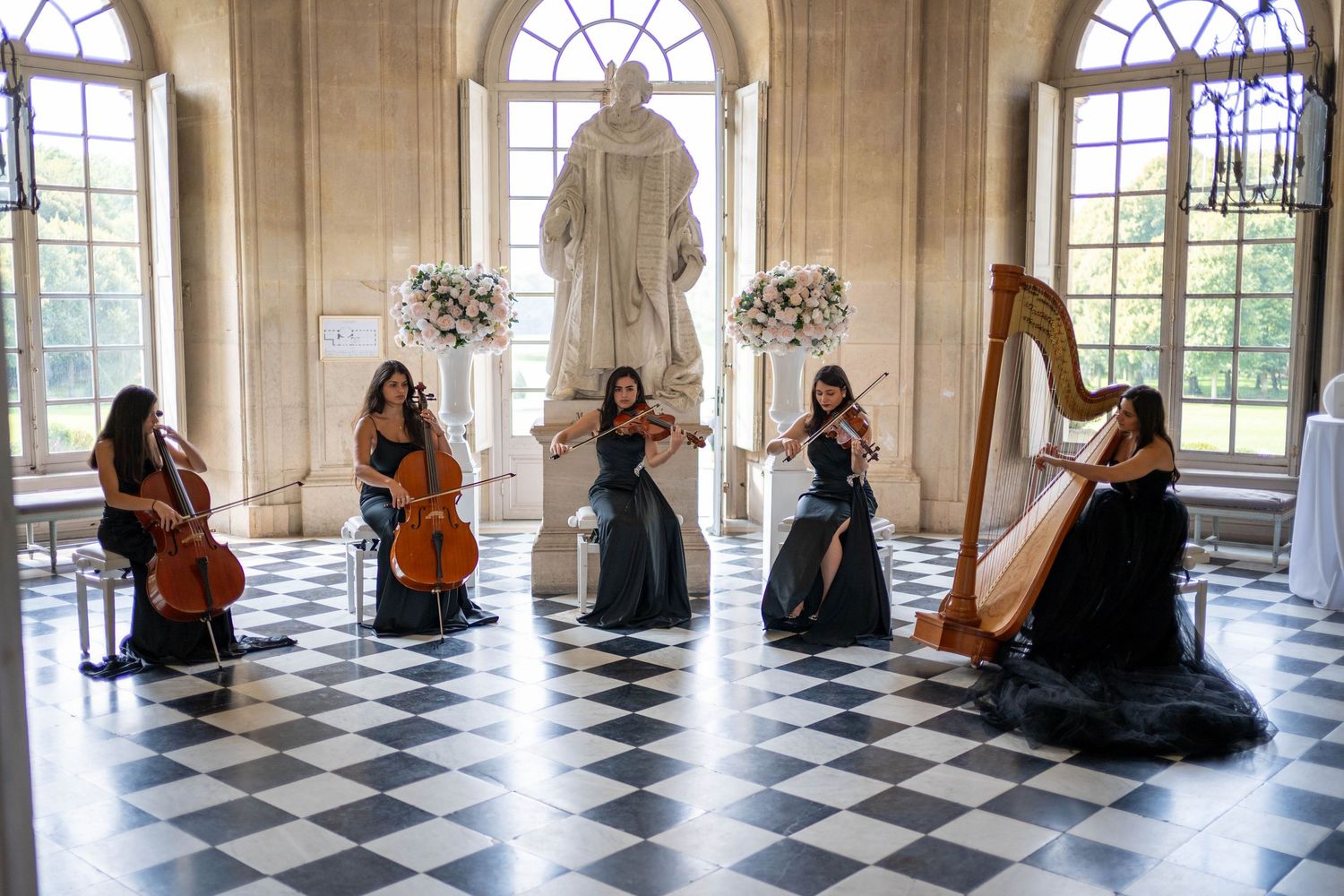 Musicians with instruments sit along arched windows in a grand checkered-floor ballroom.