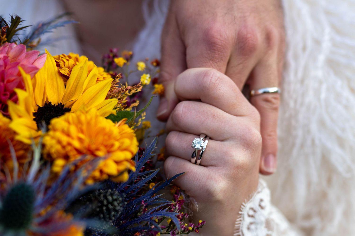 Close-up of wedding rings and yellow sunflower bouquet details.