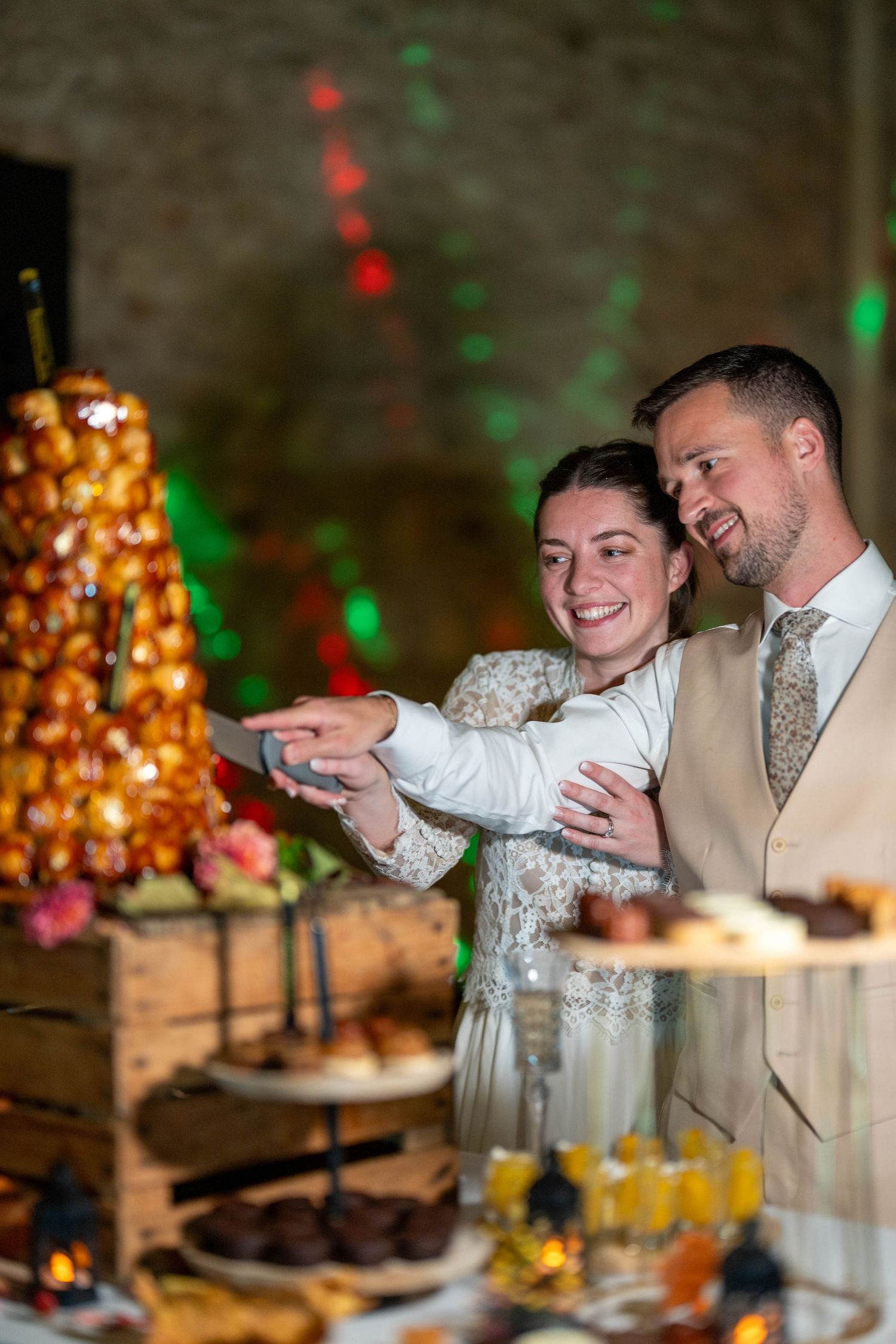 Wedding reception dessert table with colorful lighting and festive decorations.