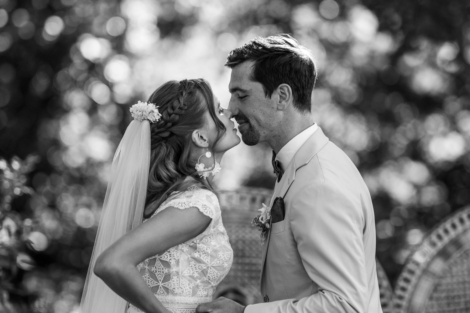 A couple shares an intimate moment during their outdoor wedding ceremony with soft bokeh lighting in the background.