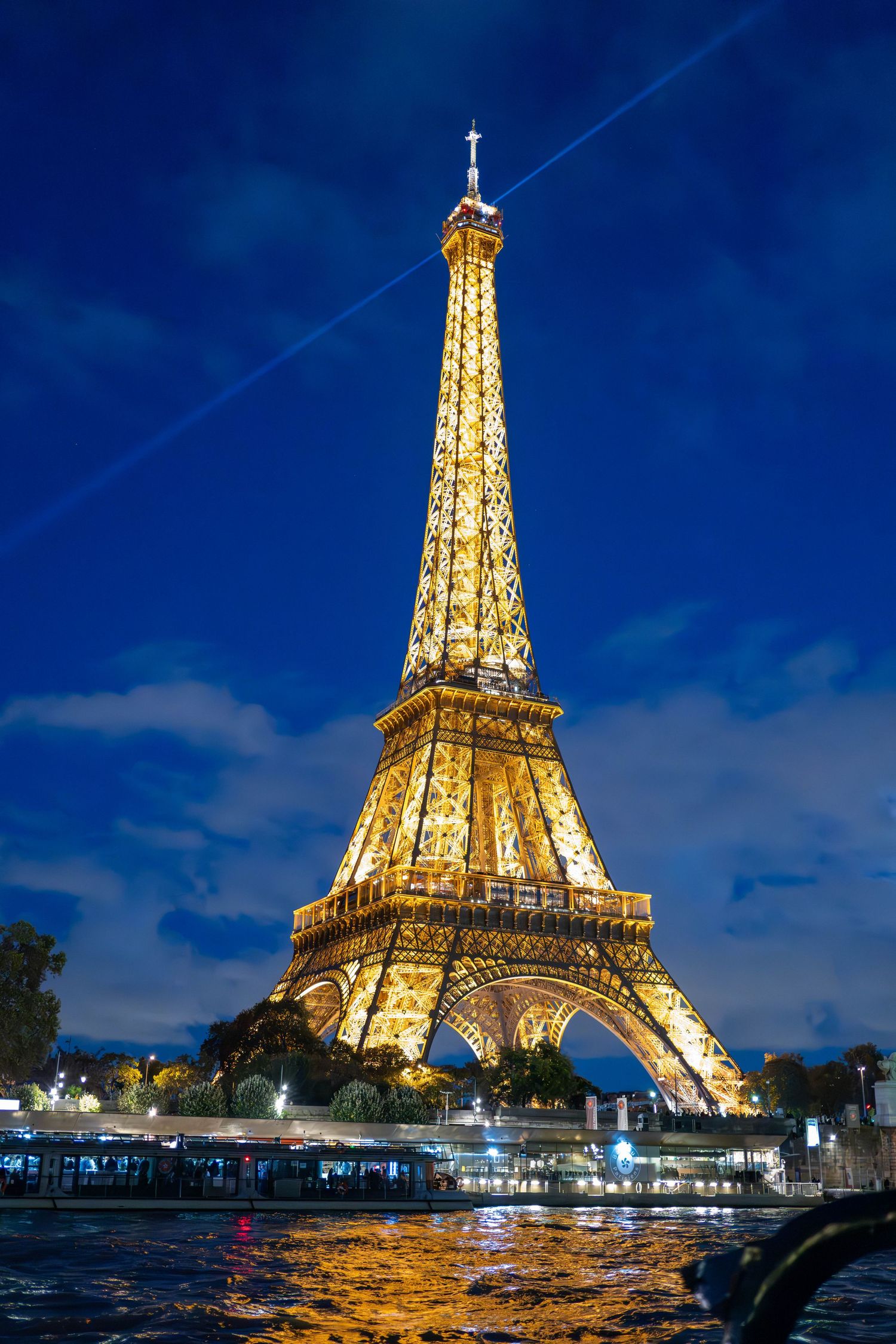Panoramic sequence showing the illuminated Eiffel Tower at dusk reflecting golden lights on the Seine River in Paris.